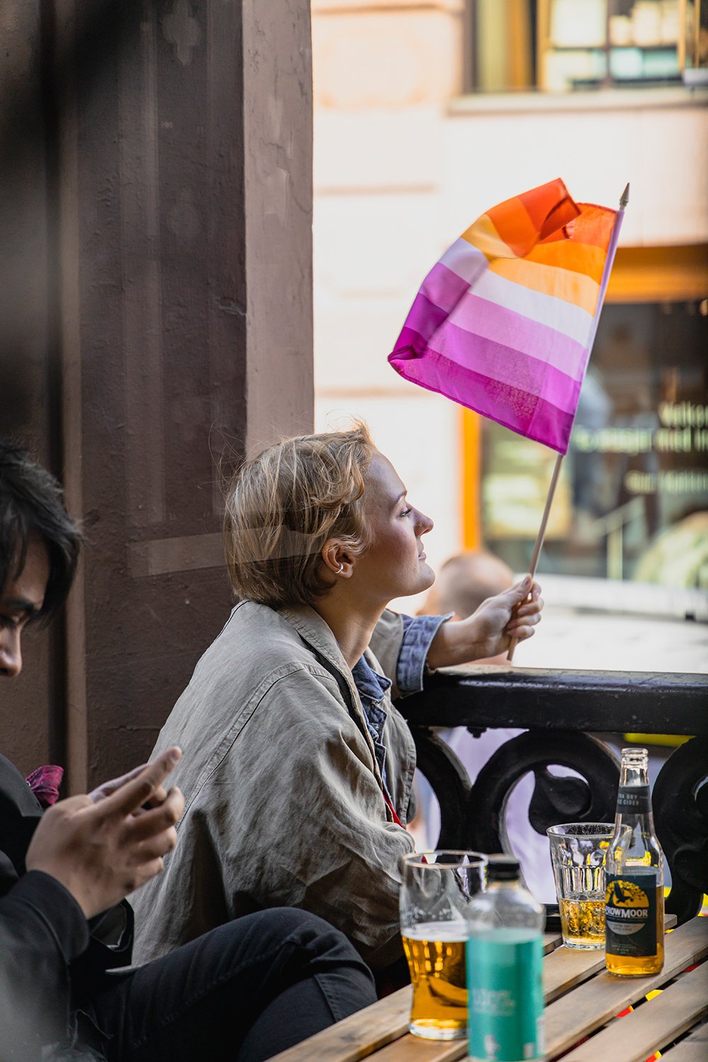 En jente som holder et Pride-flagg og nyter utsikten fra restaurant Bacchus i Oslo sentrum