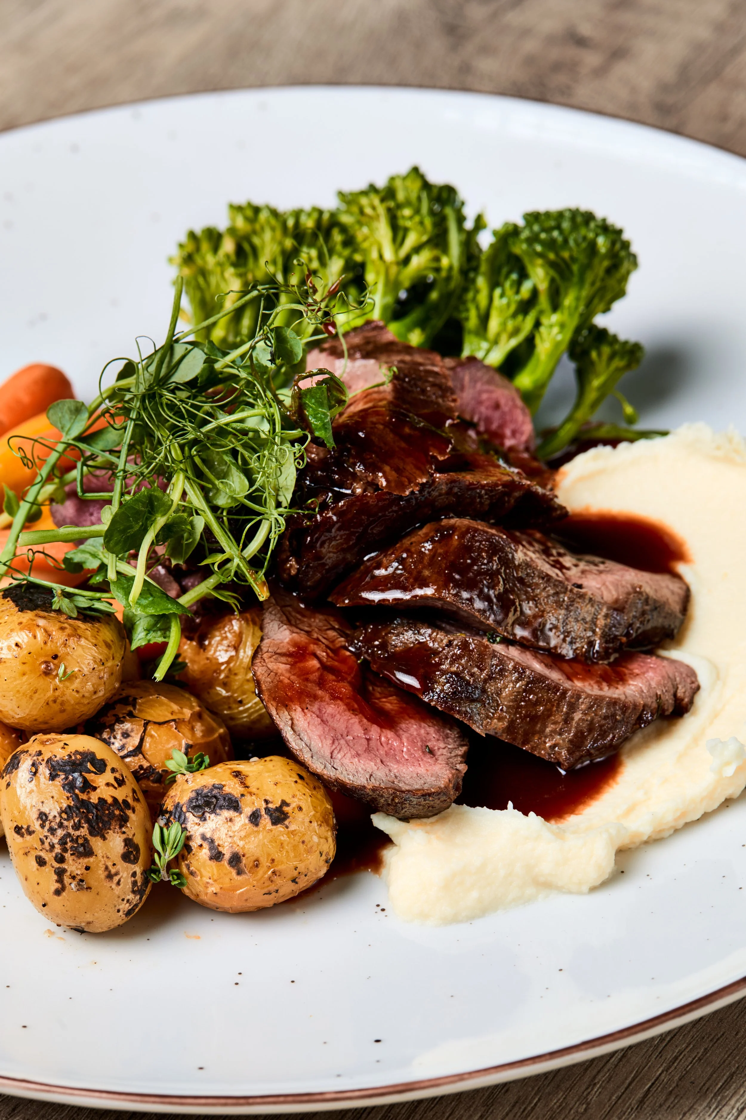 Bilde av biff, poteter, brokkolini, agurk og rødvinsaus servert med potetmos - matfoto