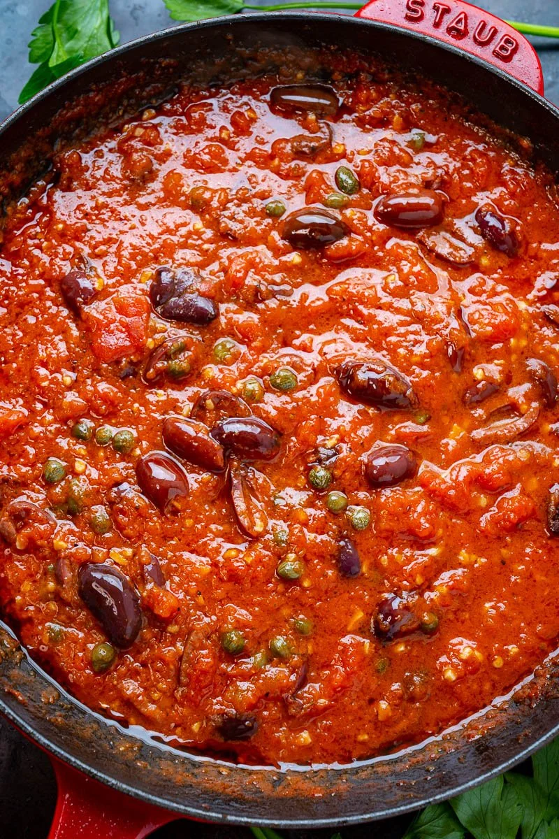 A close-up of a skillet filled with homemade vegetable chili, featuring kidney beans, green peas, and tomato sauce.