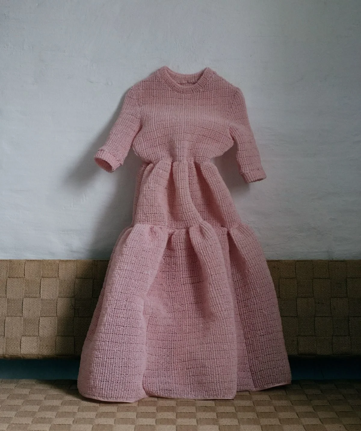 Pink knitted dress hanging against wall