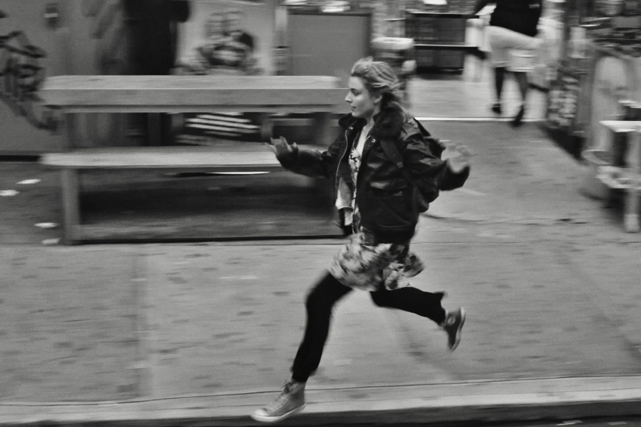 Black-and-white photo: woman running in a store from Frances Ha