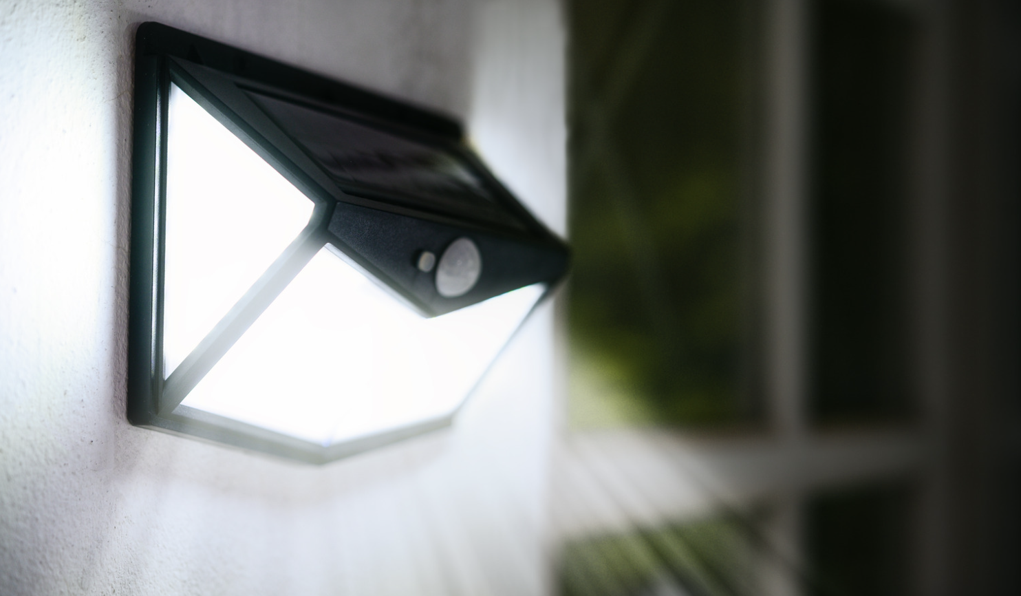 Outdoor wall-mounted solar light fixture illuminating at night.