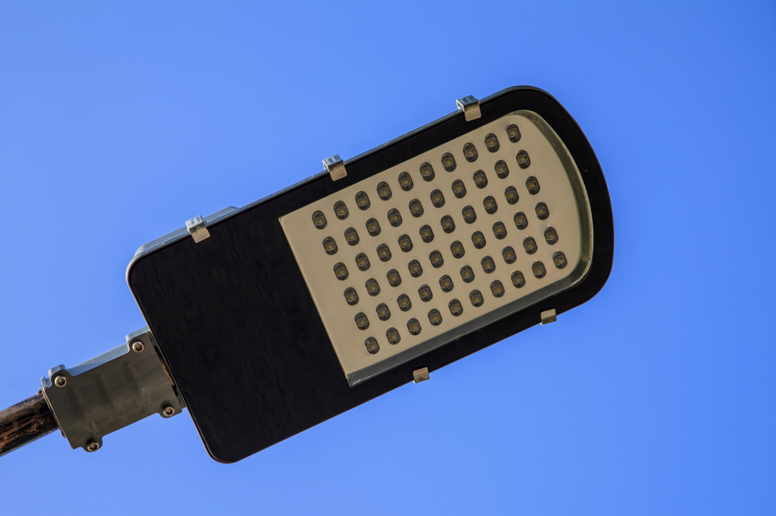 Close-up of an LED street light against a clear blue sky.