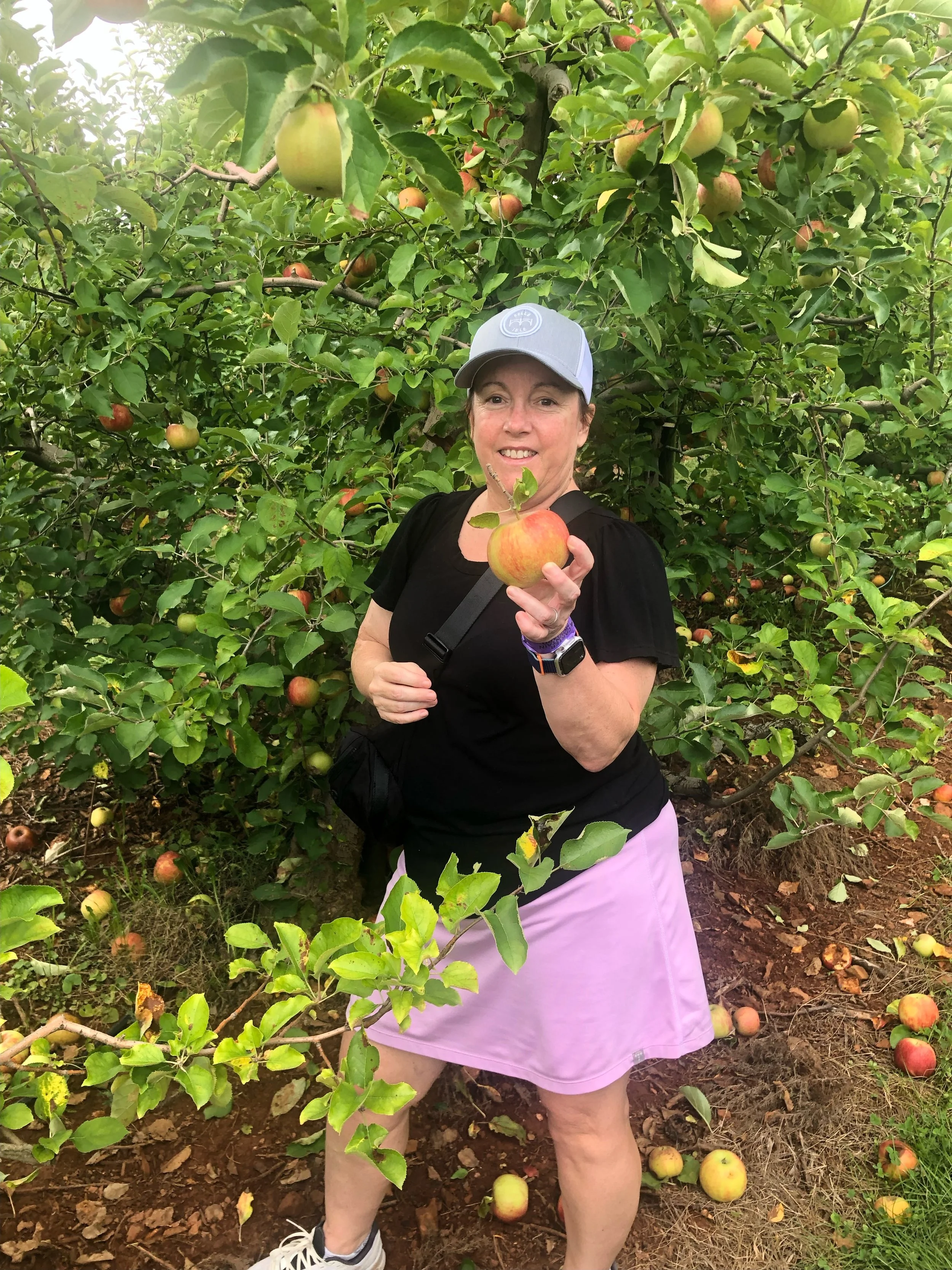 Lisa holding an apple in an orchard