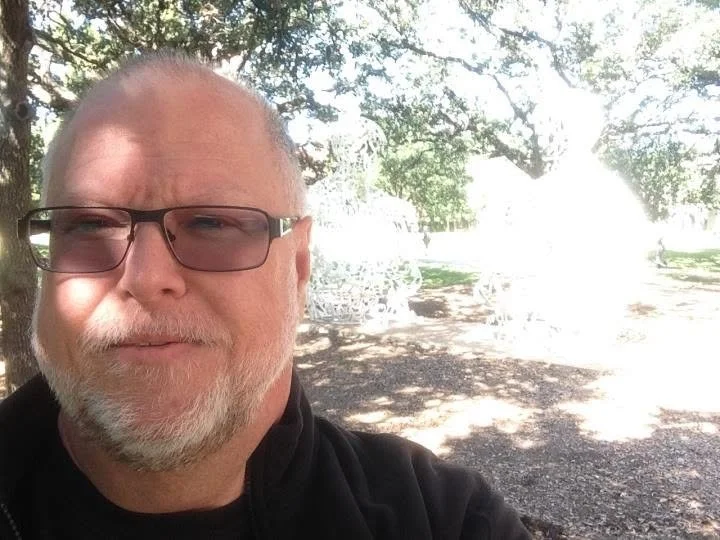 Portrait of a bearded man wearing sunglasses outdoors beneath oak trees