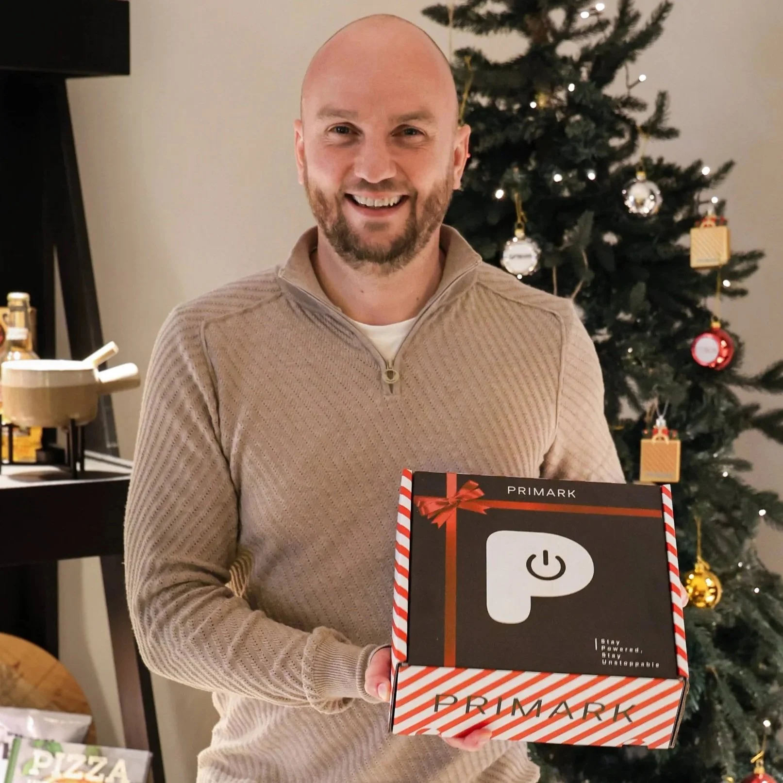 Zwart-wit portret van een glimlachende man met bril, gekleed in een casual blazer en een zwarte turtleneck, tegen een zwarte achtergrond.