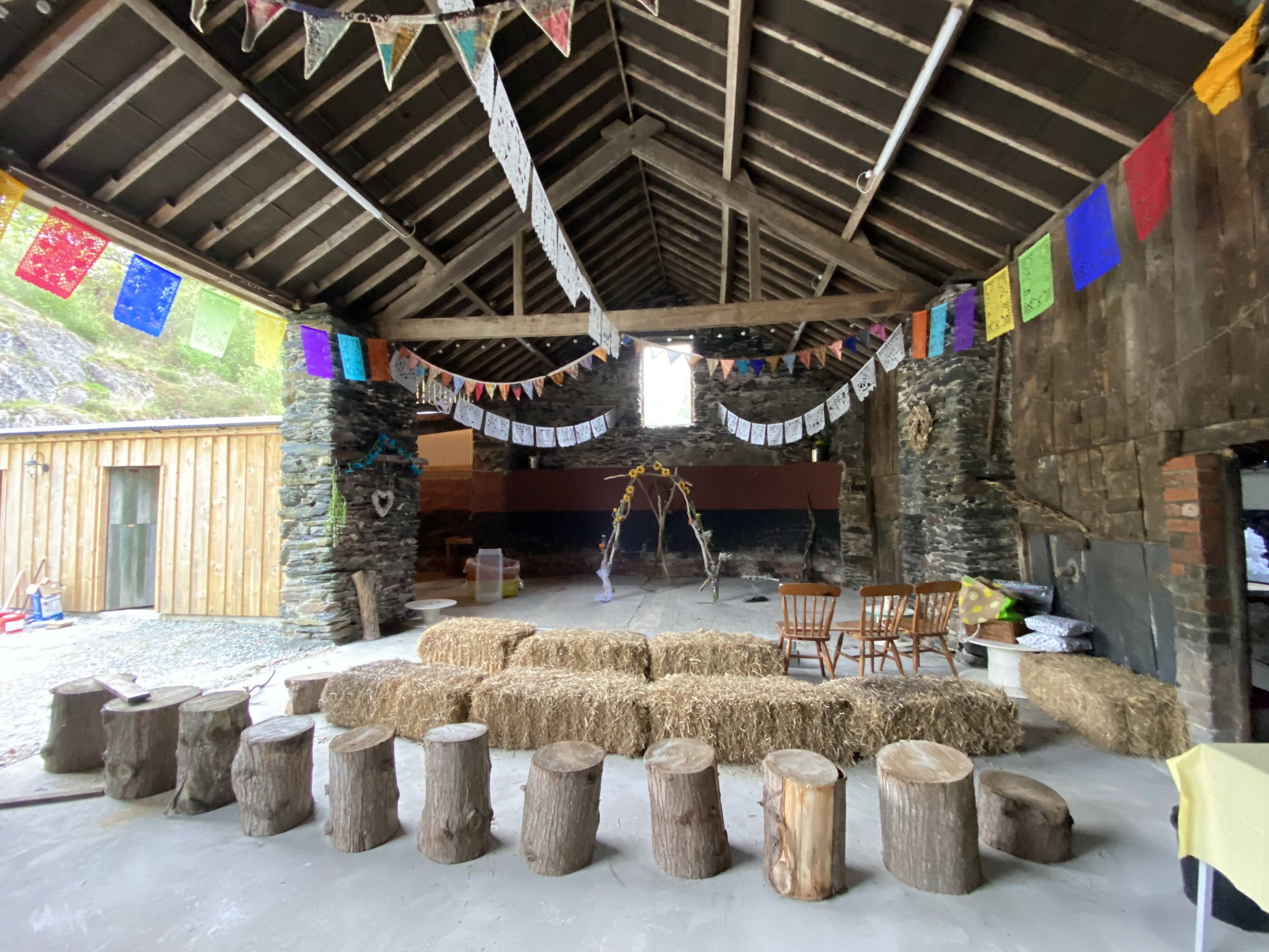 barn dressed for an event with log seats, colourful bunting, hay bales