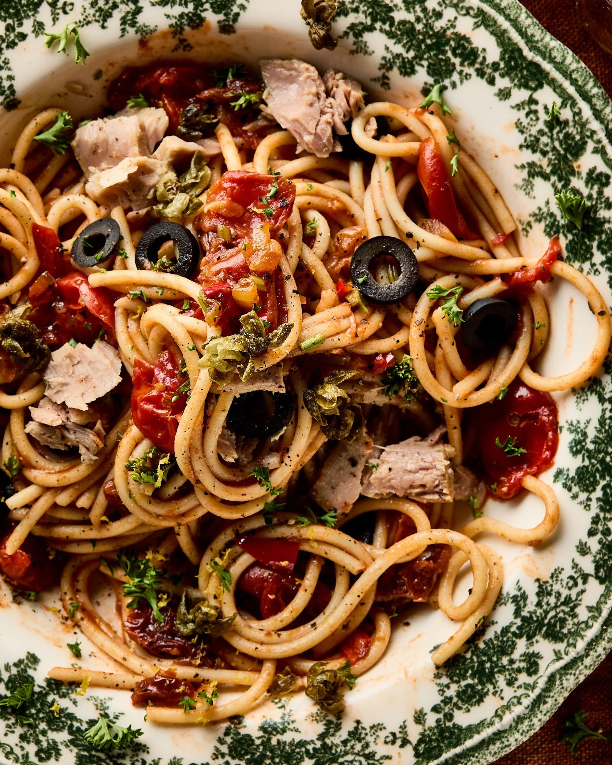 Close up Spaghetti alla puttanesca, frisse zomerse pasta klassieker met ansjovis, tonijn en gefrituurde kappertjes, in 30 minuten op tafel
