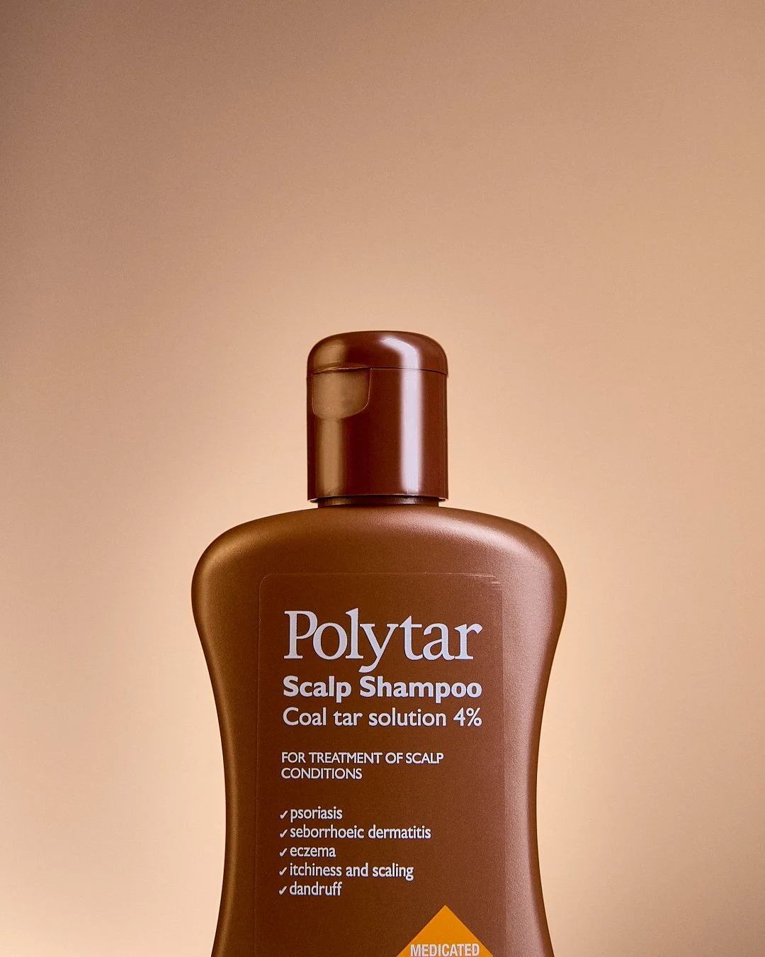 Brown bottle of Polytar scalp shampoo with a beige background.