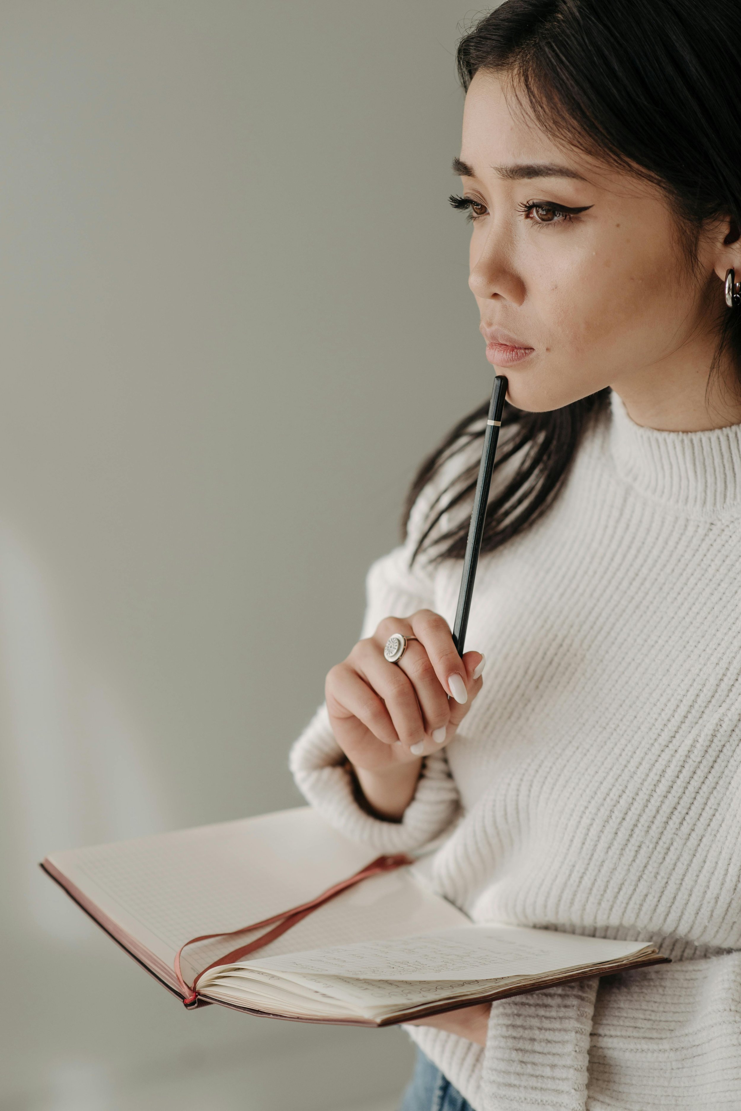 Woman standing in thought holding a notebook and pencil, representing neurodivergent affirming therapy in Sierra Madre, CA