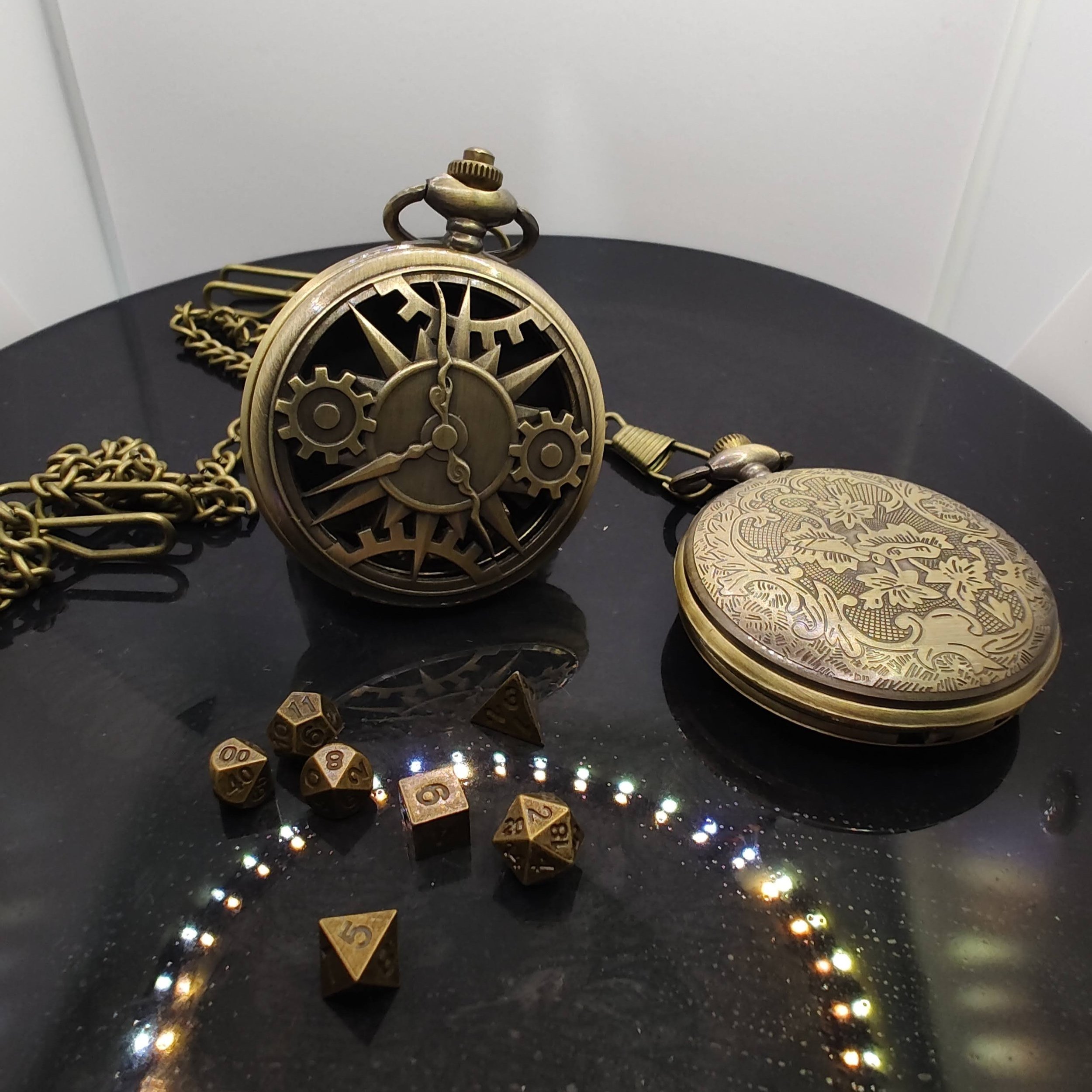 Bronze steampunk-style pocket watch adorned with clockwork gears, resting on a black surface next to a miniature set of metal dice for DnD and Pathfinder
