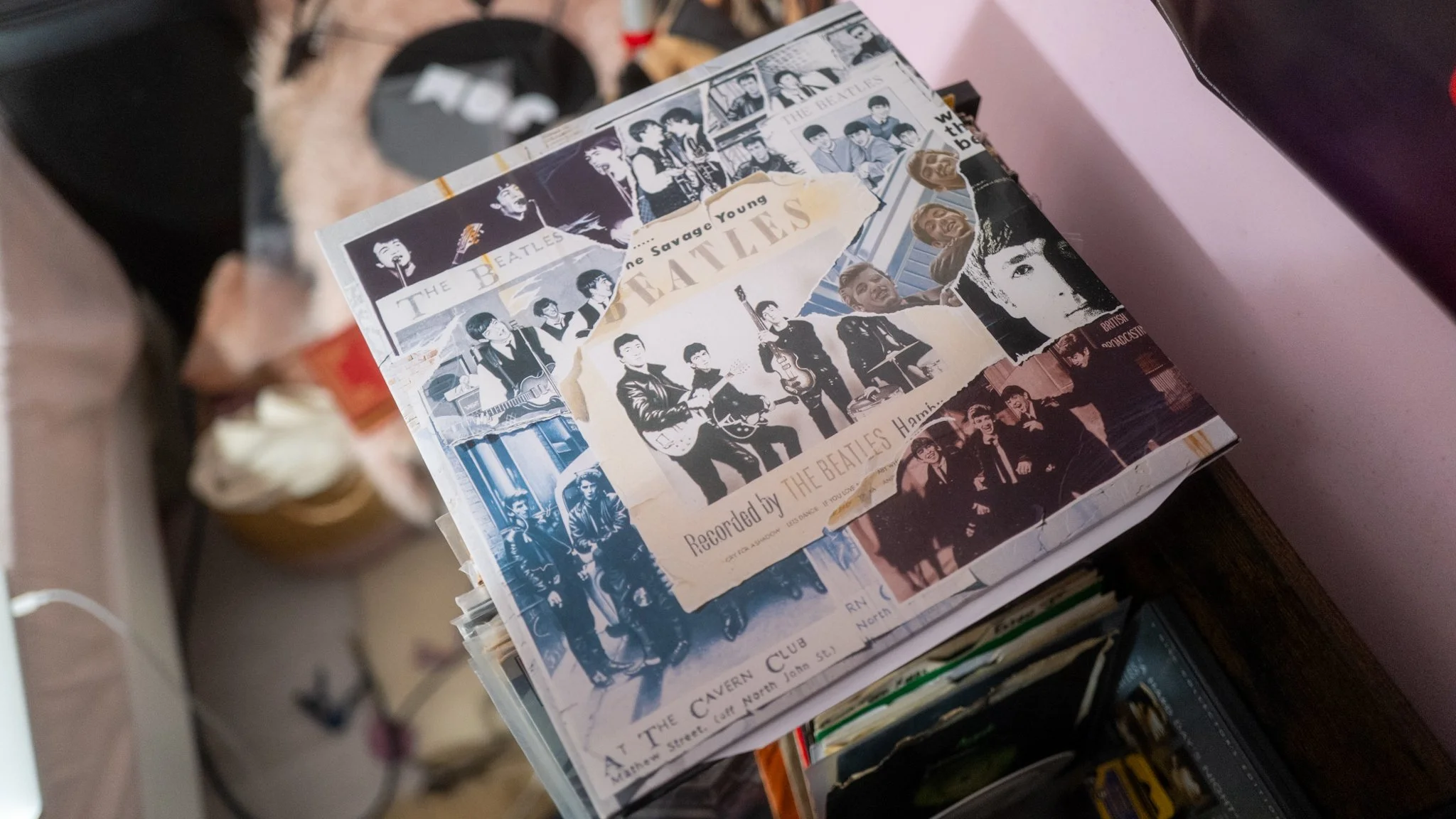 A collection of Beatles-related photos and memorabilia, including concert images, album covers, and handwritten notes, arranged in a collage on top of a cabinet.