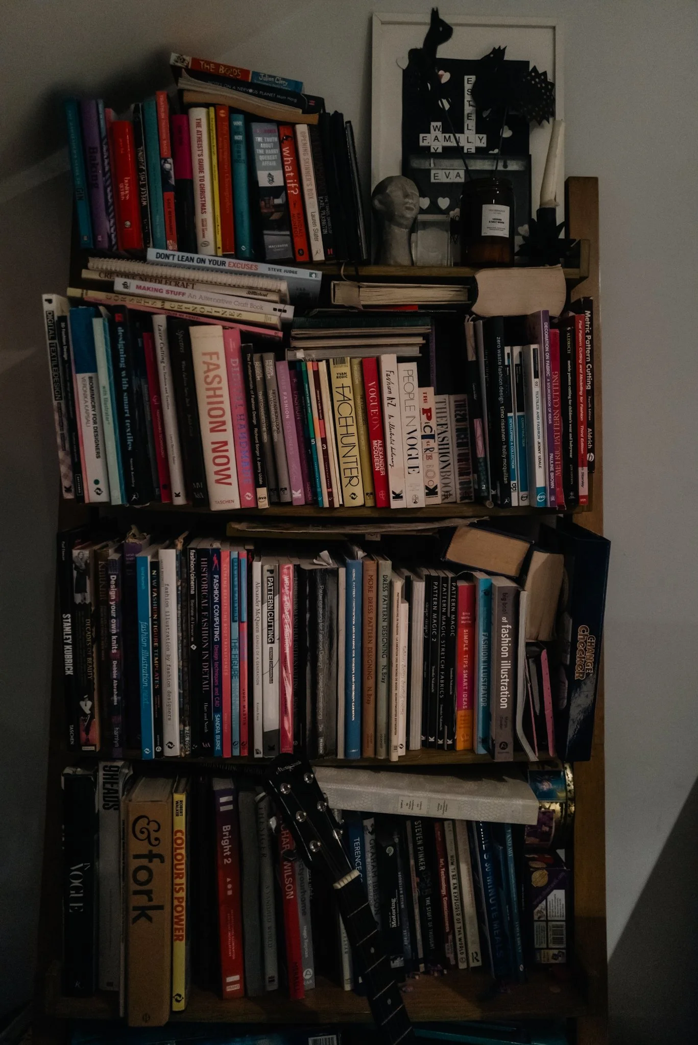 Bookshelf filled with fashion, photography, art, and lifestyle books, a guitar, and wall decorations.