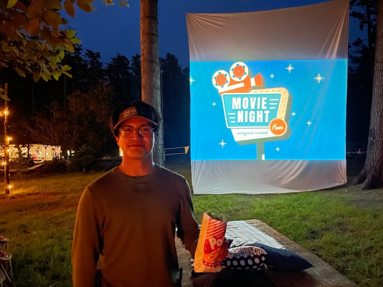 man holding popcorn with outdoor movie projected stretched fabric