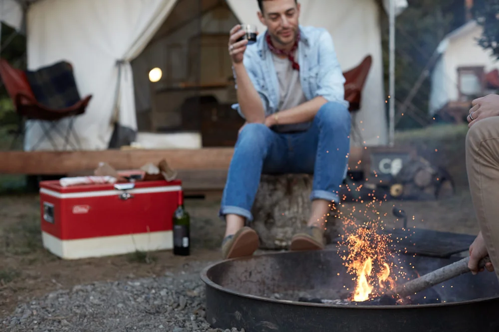  Someone sitting in front of campfire tent with red coolor nearby 