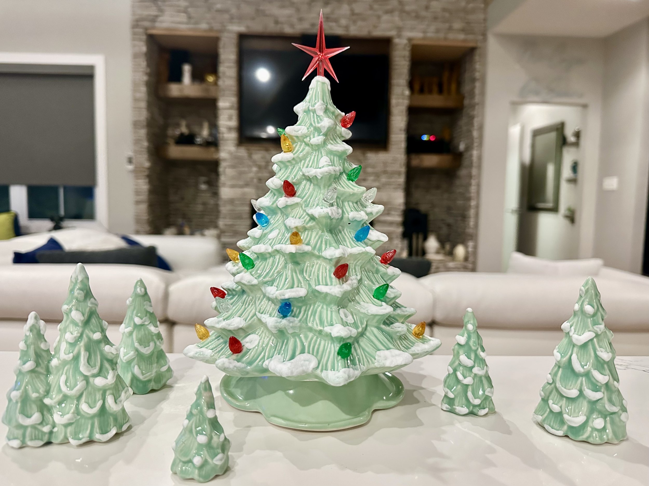 Two vintage Christmas trees, one dark green with multicolored lights and one light green with red berries, decorated with star toppers