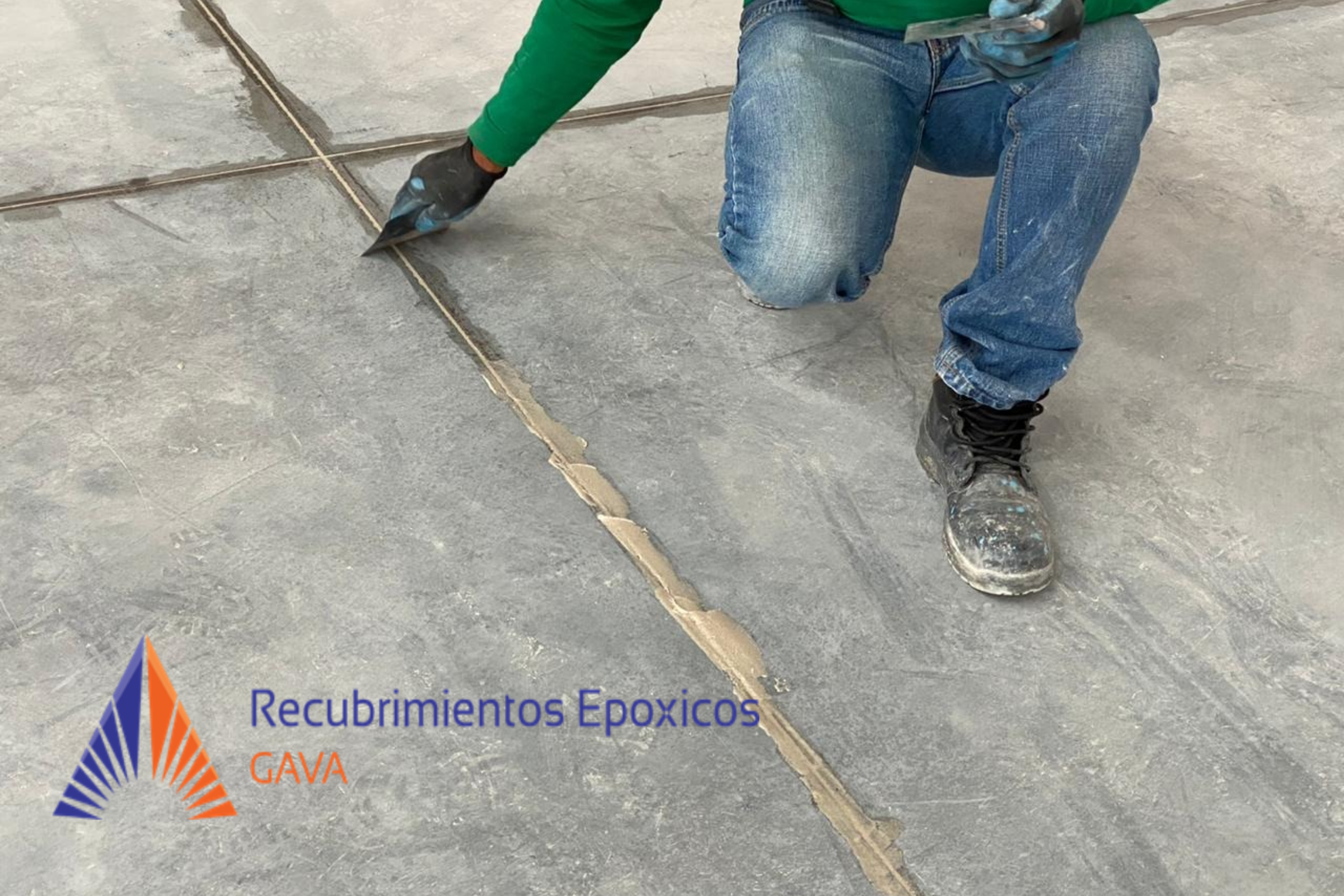 Trabajo en suelo con baldosas de epóxico y las manos de un trabajador usando guantes negros y botas orthopédicas negras, con las herramientas en las manos, trabajando en la instalación de baldosas epóxicas.