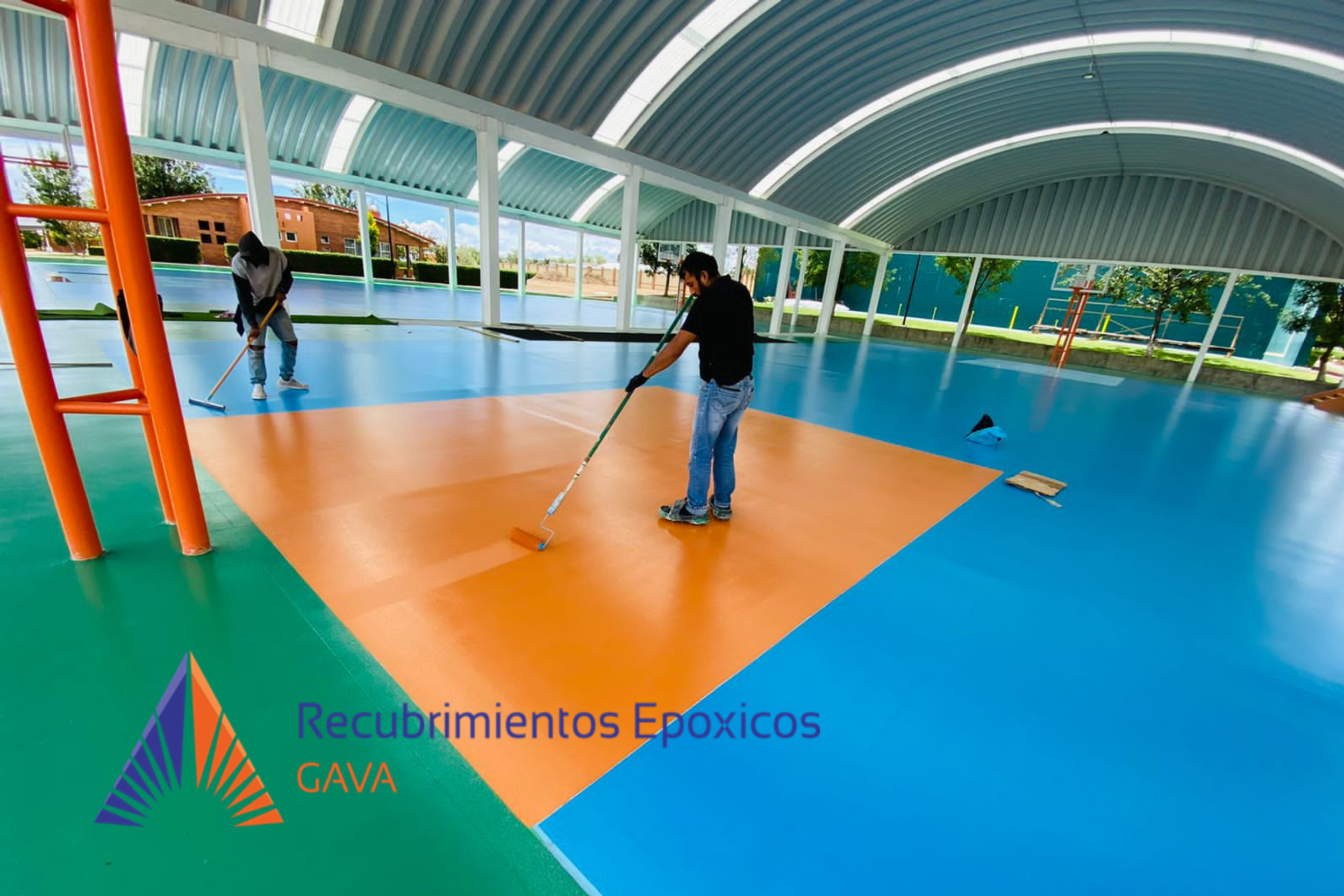 Dos personas pintando un piso en un espacio cubierto con estructura metálica y domo de acrílico, con texto en la esquina inferiore izquierda que dice 'Recubrimientos Tóxicos GAVA'.