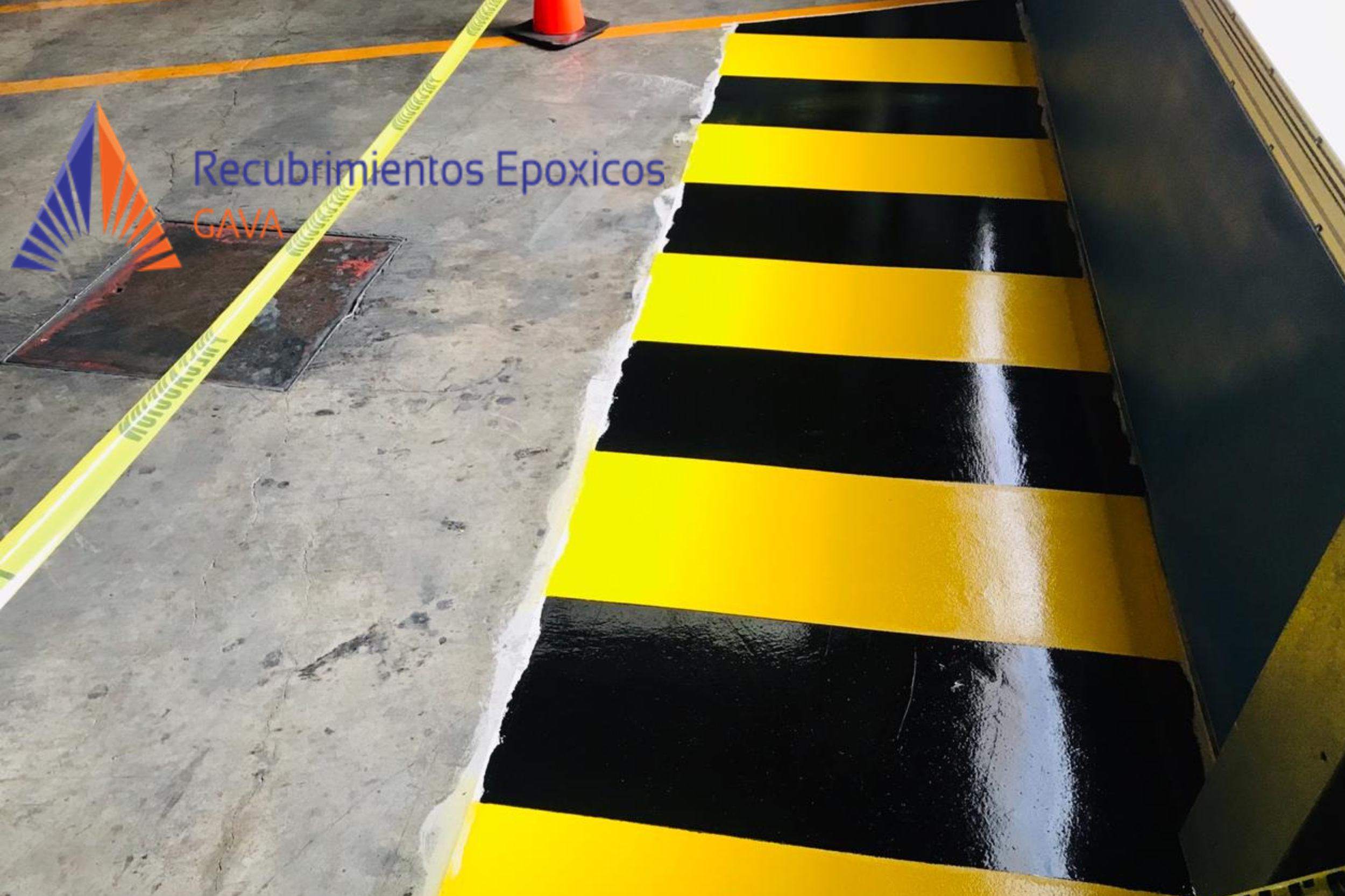 Piso de estacionamiento con línea blanca y área con pintura amarillo y negro para protección, además de señalización de cinta en amarillo.