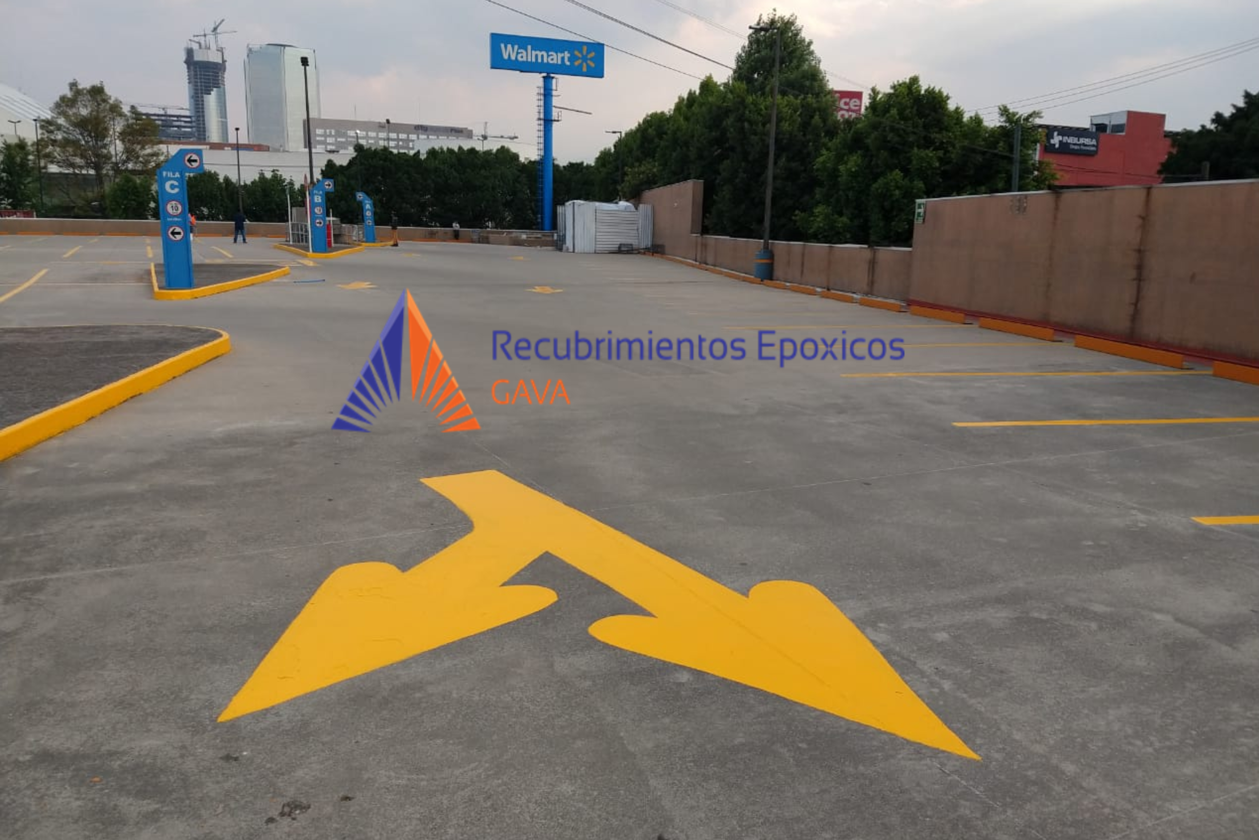 Estacionamiento vacío con marcas amarillas y señalizaciones, en el fondo un cartel de Walmart y algunos edificios altos.