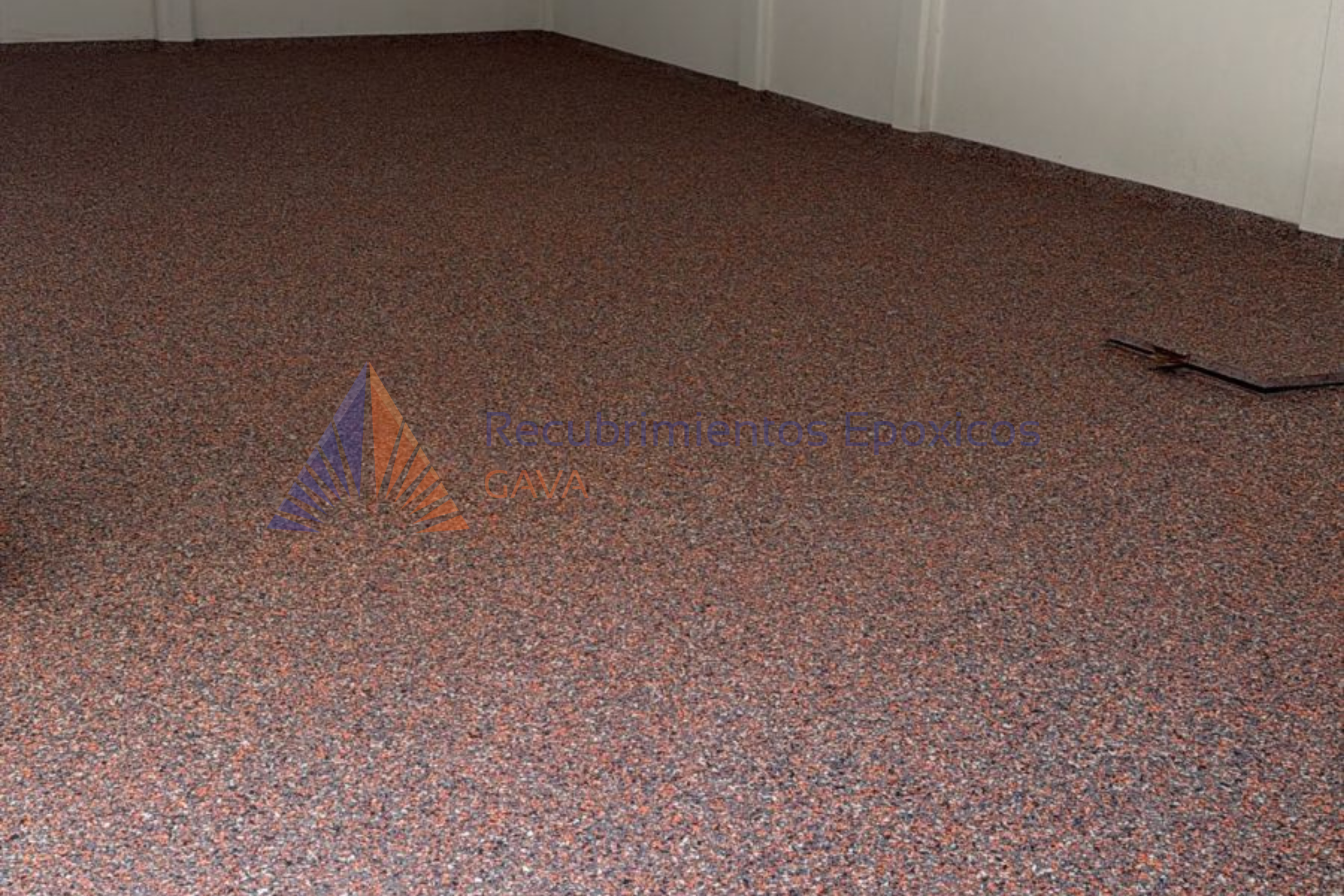 Piso de recubrimiento epóxico de color rojo, en una habitación con paredes blancas y una pequeña rendija en el piso.