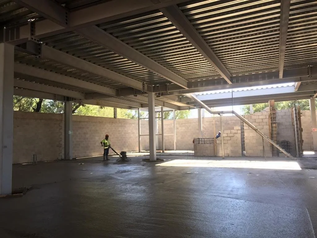 trabajador usando una máquina para alisar el concreto en un espacio de construcción de un edificio.