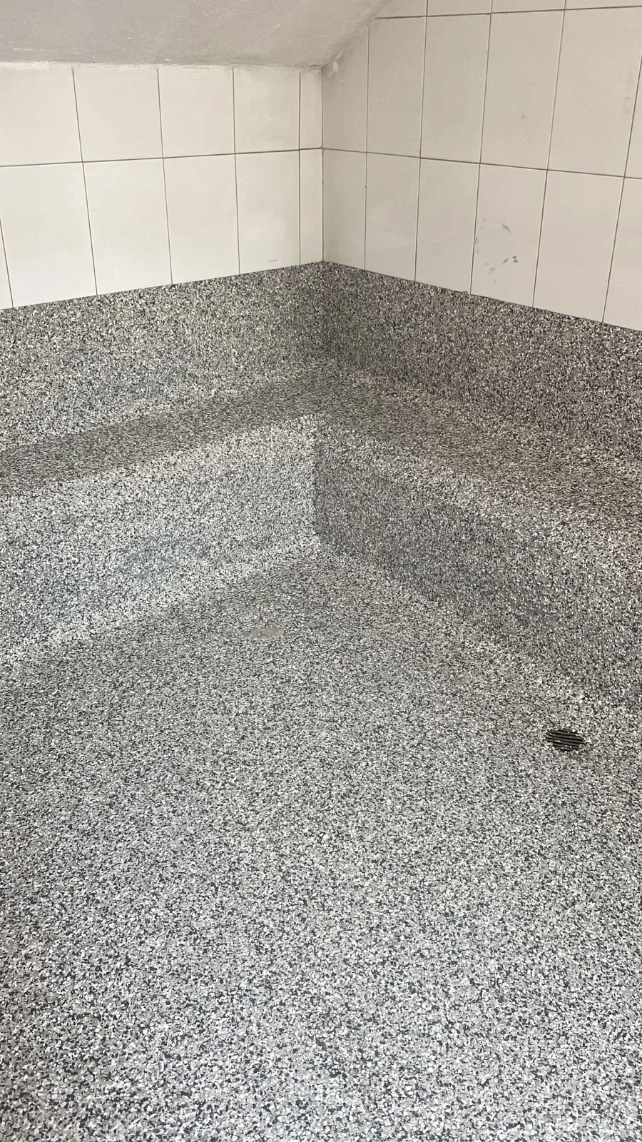 Piso de baldosas de granito y paredes de azulejos en un baño o espacio similar.