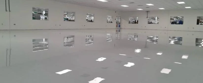 Un amplio espacio vacío en una sala con pisos reflectantes y ventanas en las paredes.