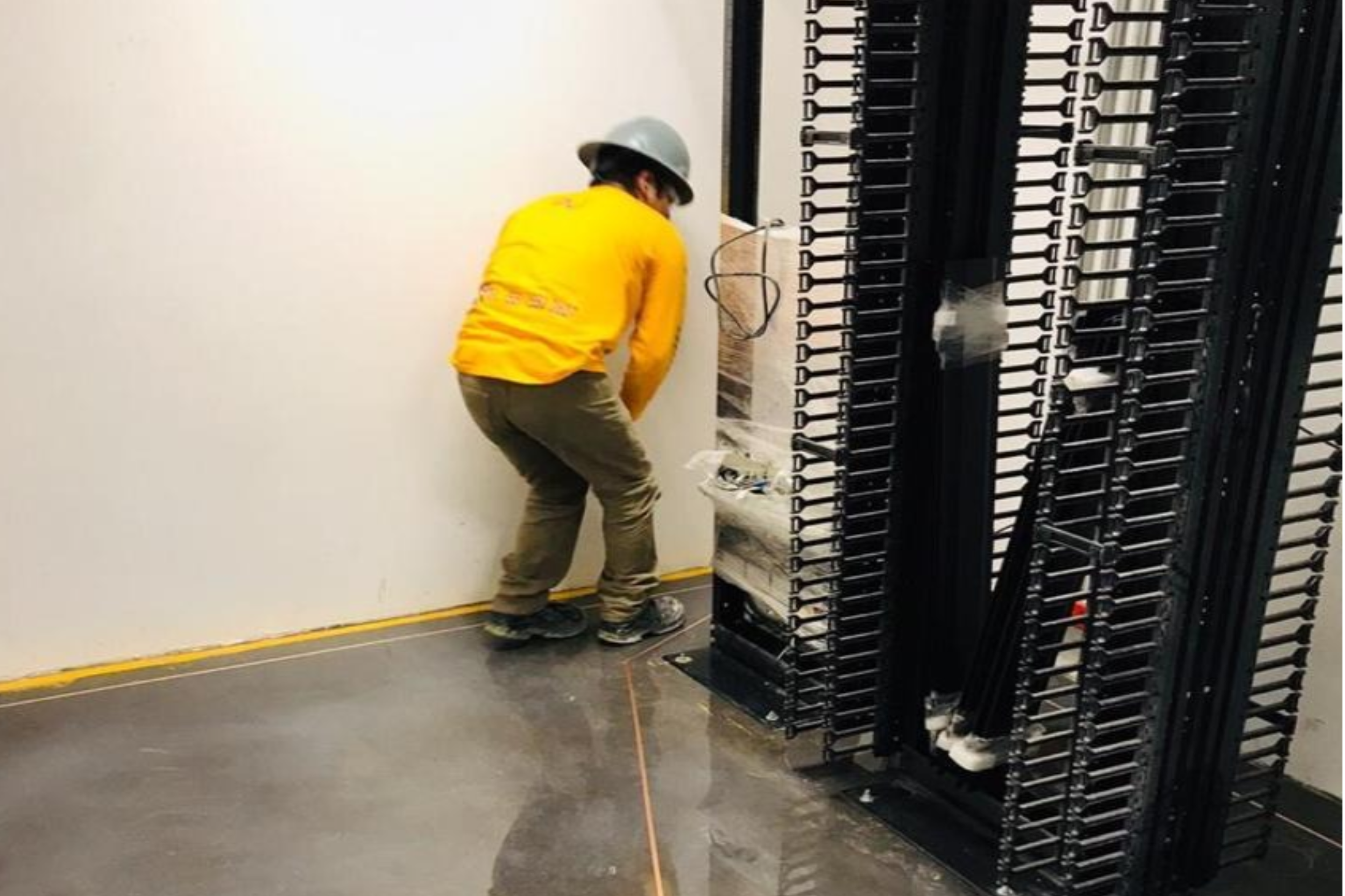 Un trabajador con casco y ropa amarilla ensamblando estructura en un área de construcción o instalación.