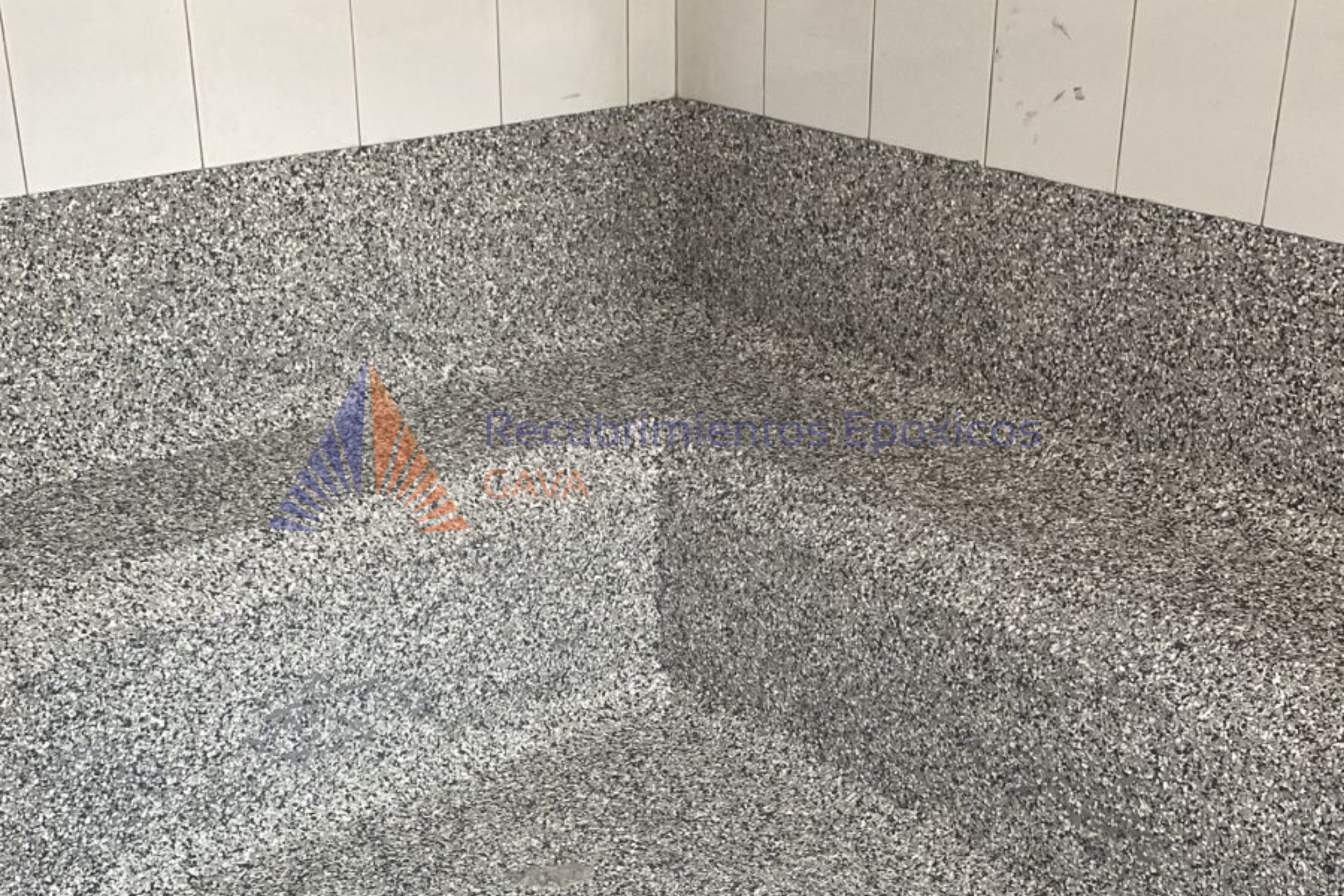 Pared de azulejos blanca y piso de granito gris.