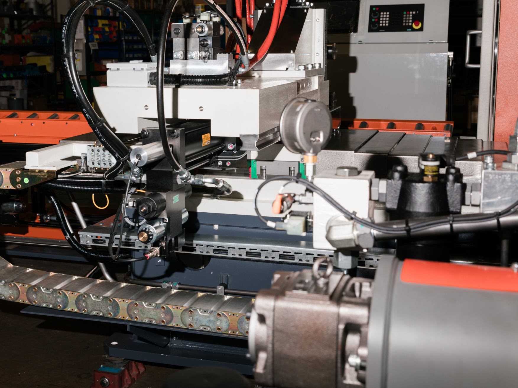 Four men stand around a large industrial machine in a factory setting, engaged in discussion. One man operates a computer console attached to the machine, while the others observe.