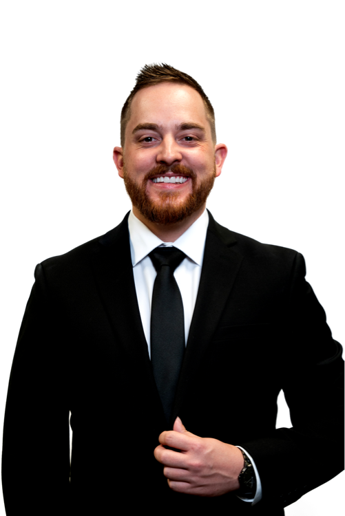 A smiling man in a black suit, white shirt, and black tie, standing against a white background.
