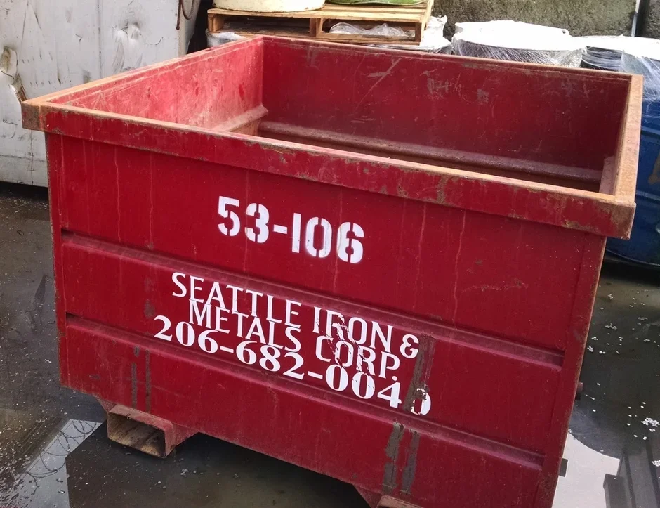 Red metal dumpster with white text listing a company name, phone number, and other details.