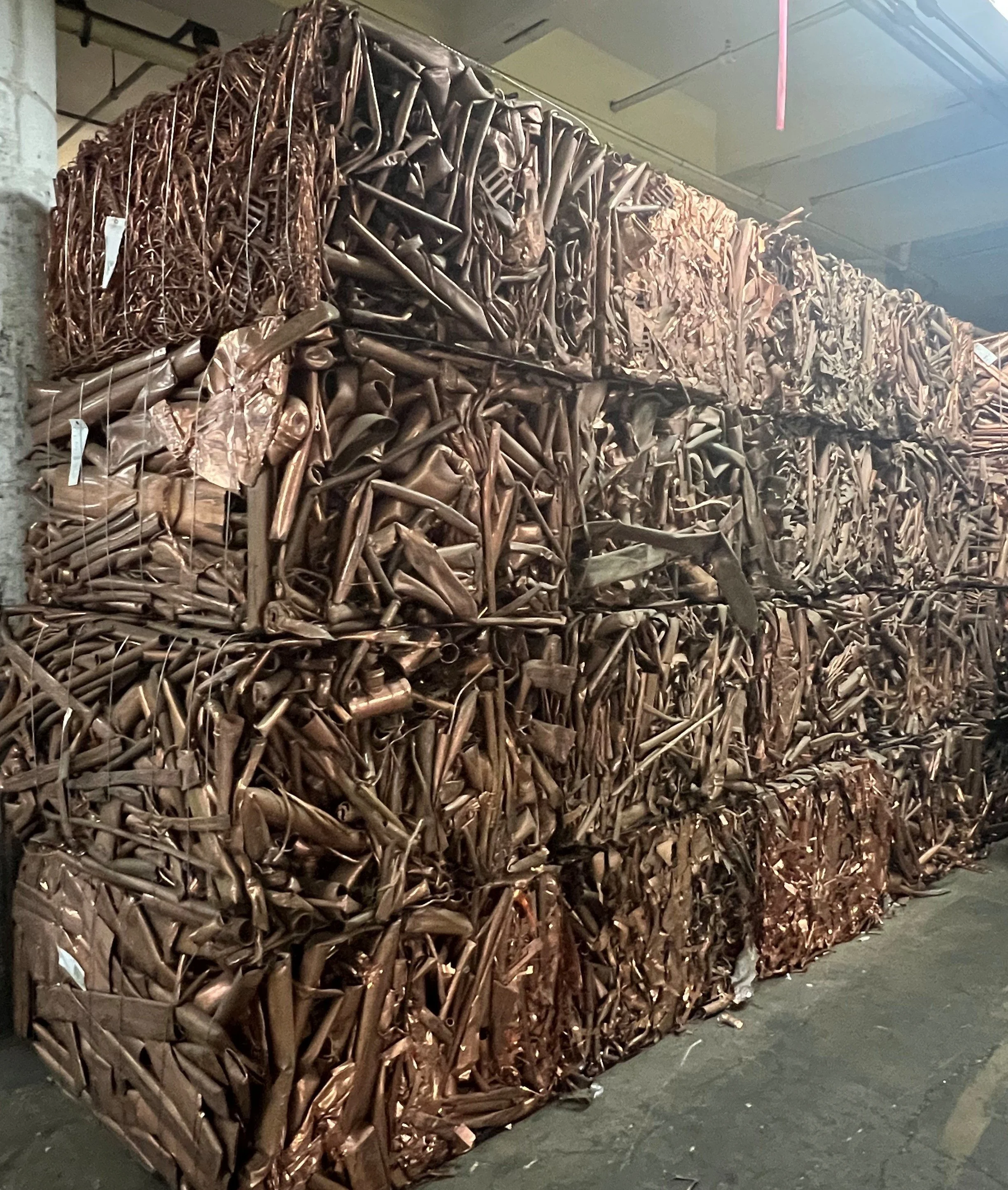 Stacks of folded or baled metal scrap in a warehouse or industrial storage area.
