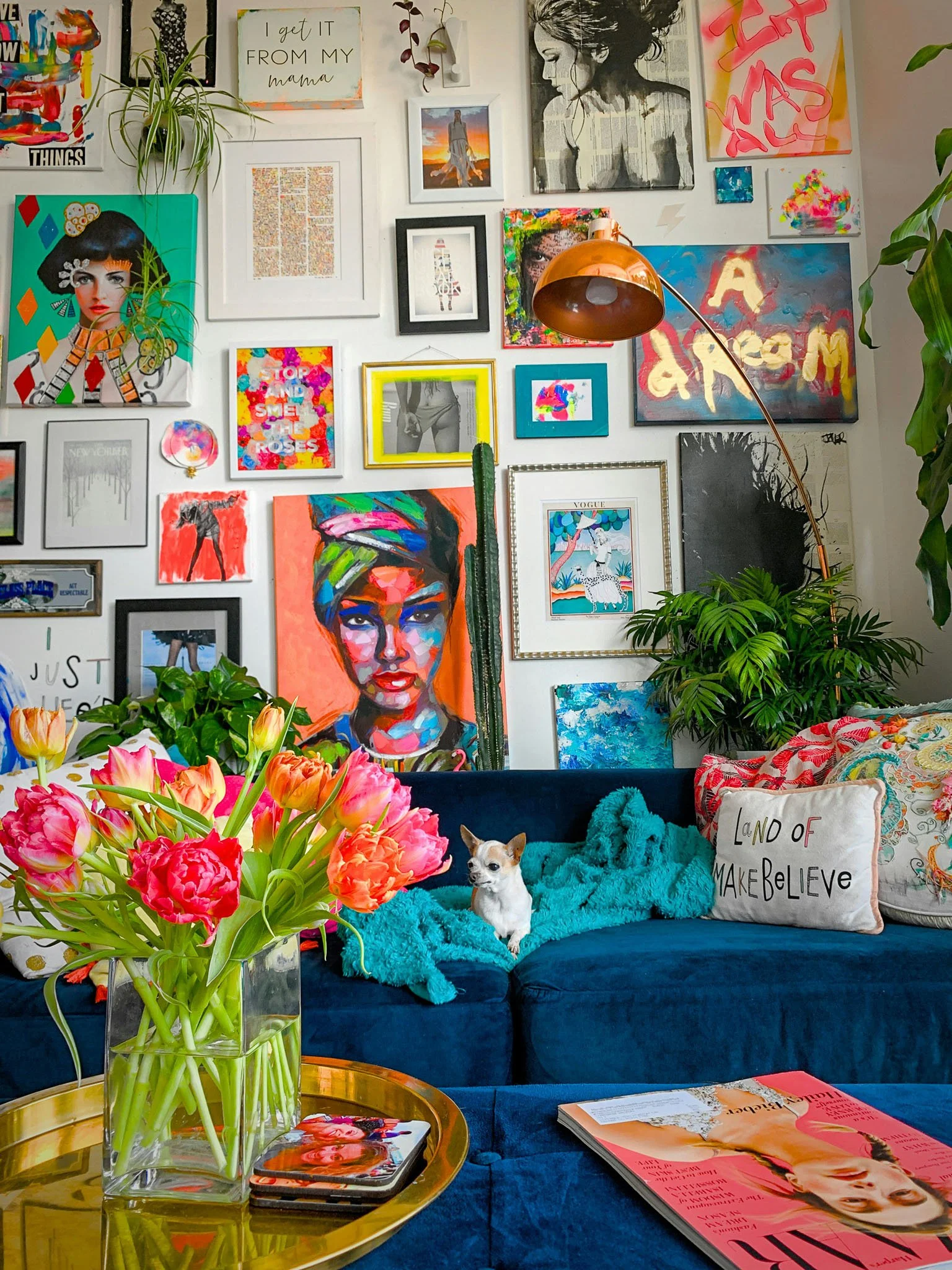 Vibrant room with colorful art gallery wall, blue couch, and flowers representing maximalist new branding approach.
