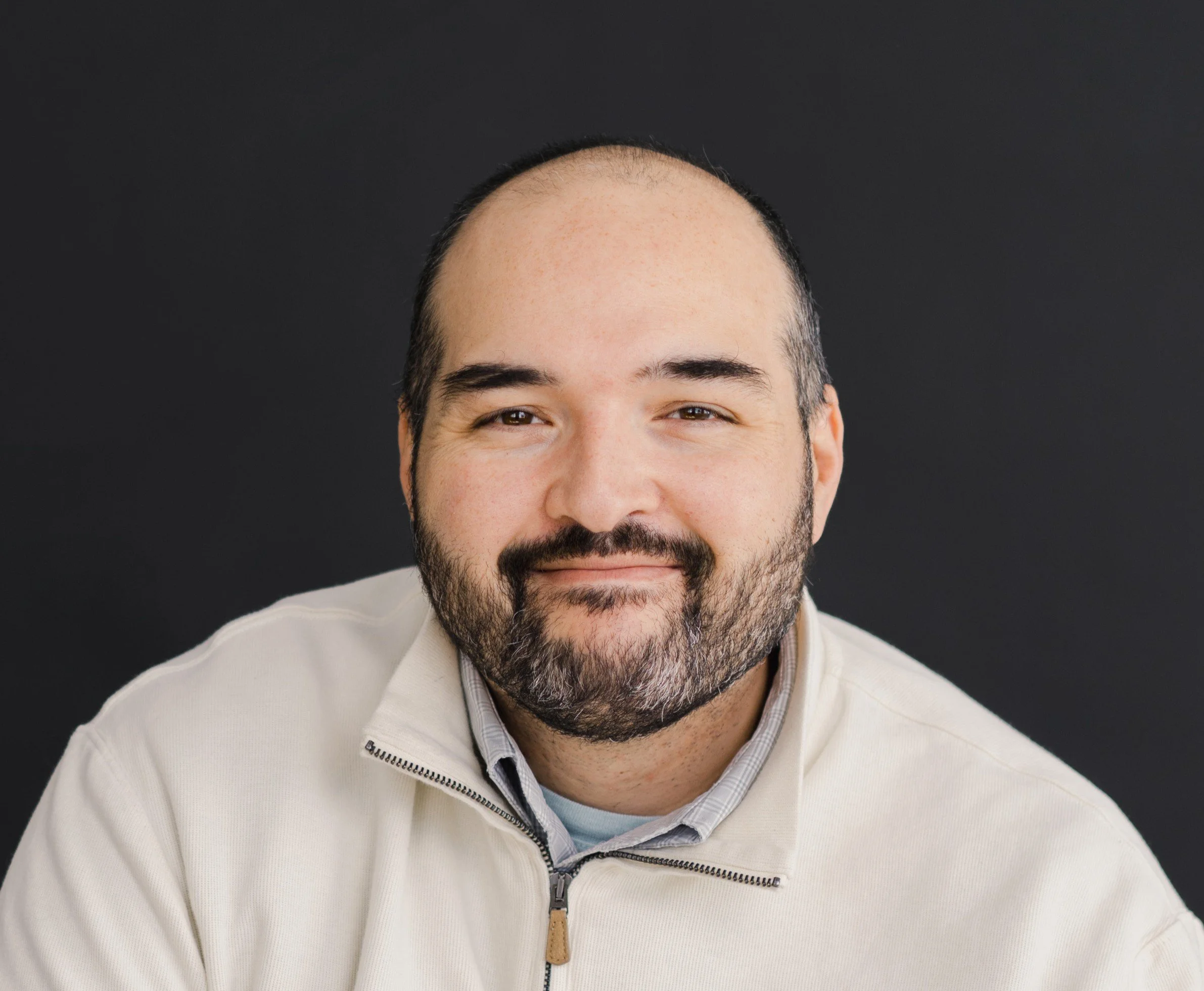 headshot of a man with a dark beard and buzz cut smiling