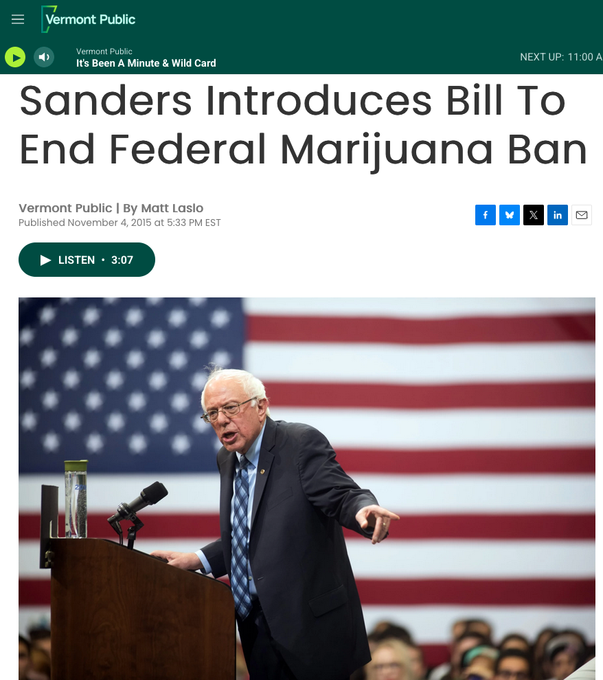 Screengrag of LCB exclusive with image if stern Bernie Sanders addressing crowd on campaign trail with large Red White and bkue flag in background