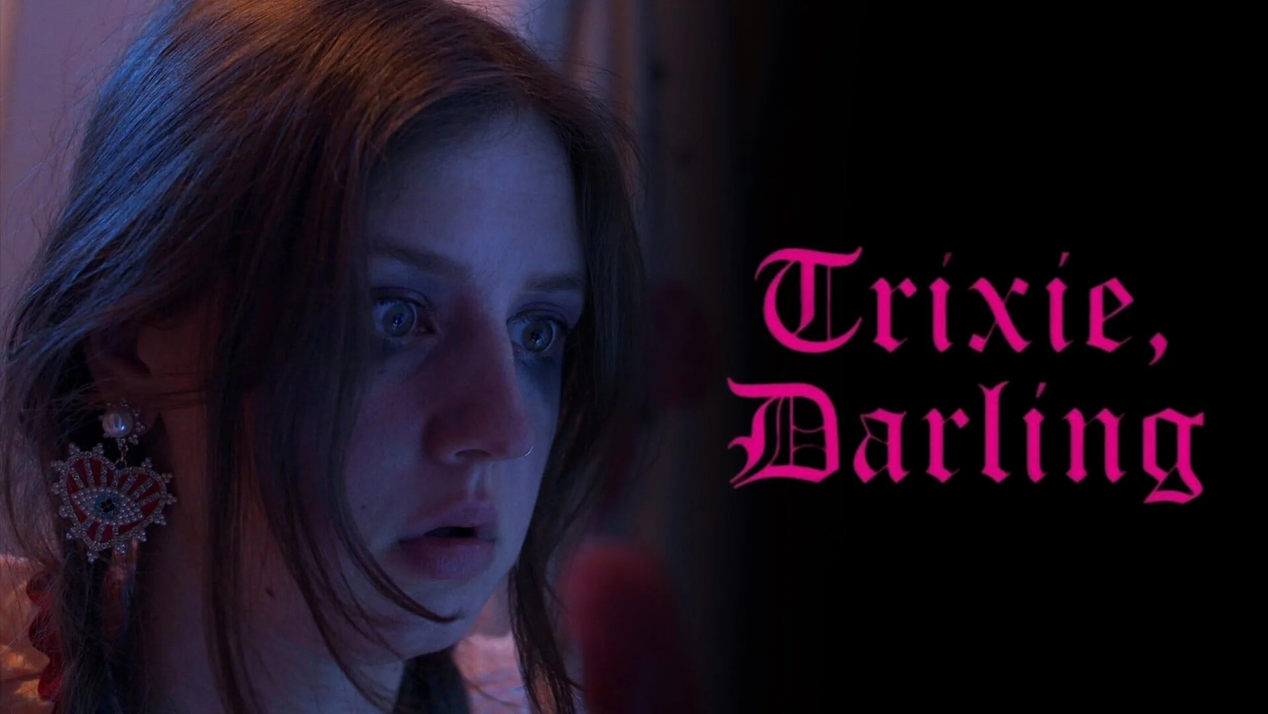 A woman with red hair and blue eyes looking surprised or scared, wearing large statement earring and studded with rhinestones, next to pink text that says 'Trixie, Darling' on a black background.