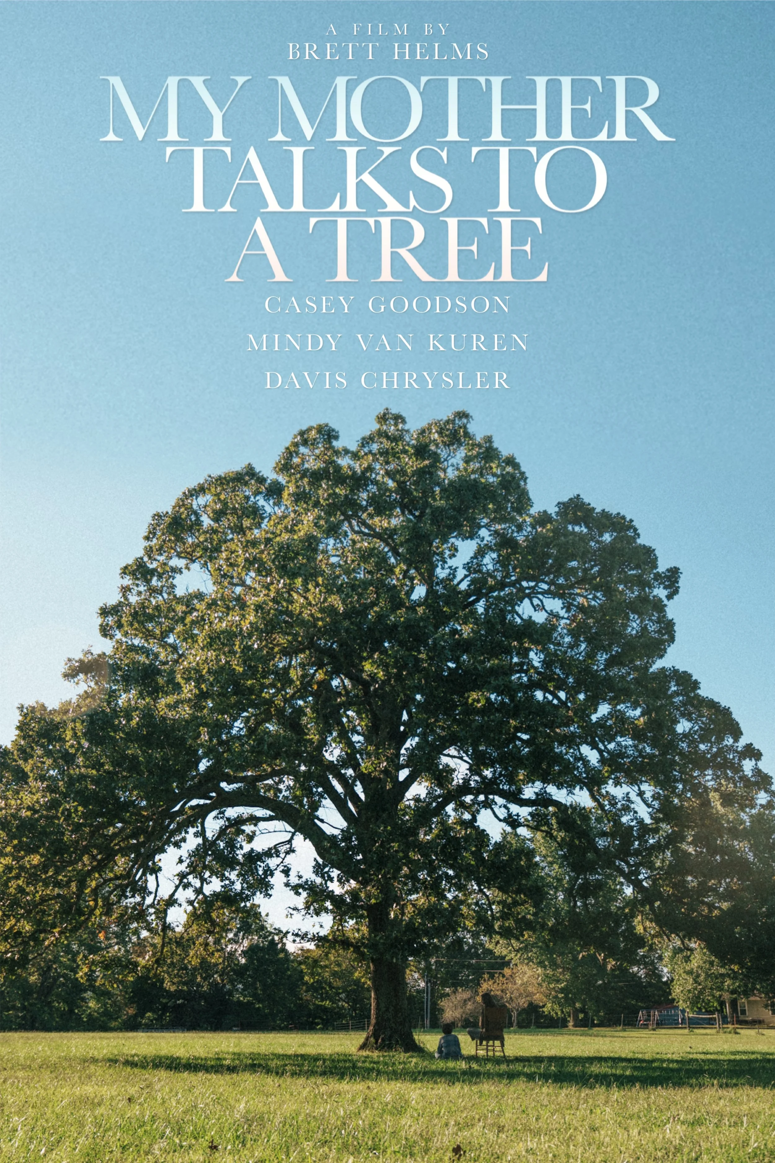 Movie poster for 'My Mother Talks to a Tree', directed by Brett Helms, featuring cast members Casey Goodson, Mindy Van Kuren, and Davis Chrysler. The background shows a large tree in a grassy field with two people sitting and one person standing near the tree, under a clear blue sky.