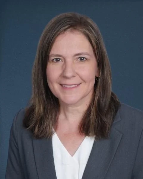 Professional headshot of Terri Erickson, PE, SE, wearing a dark blazer and white blouse, smiling against a dark background.