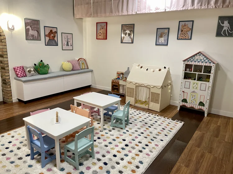 Play tent on a dotted rug, with stuffed animals on a low shelf