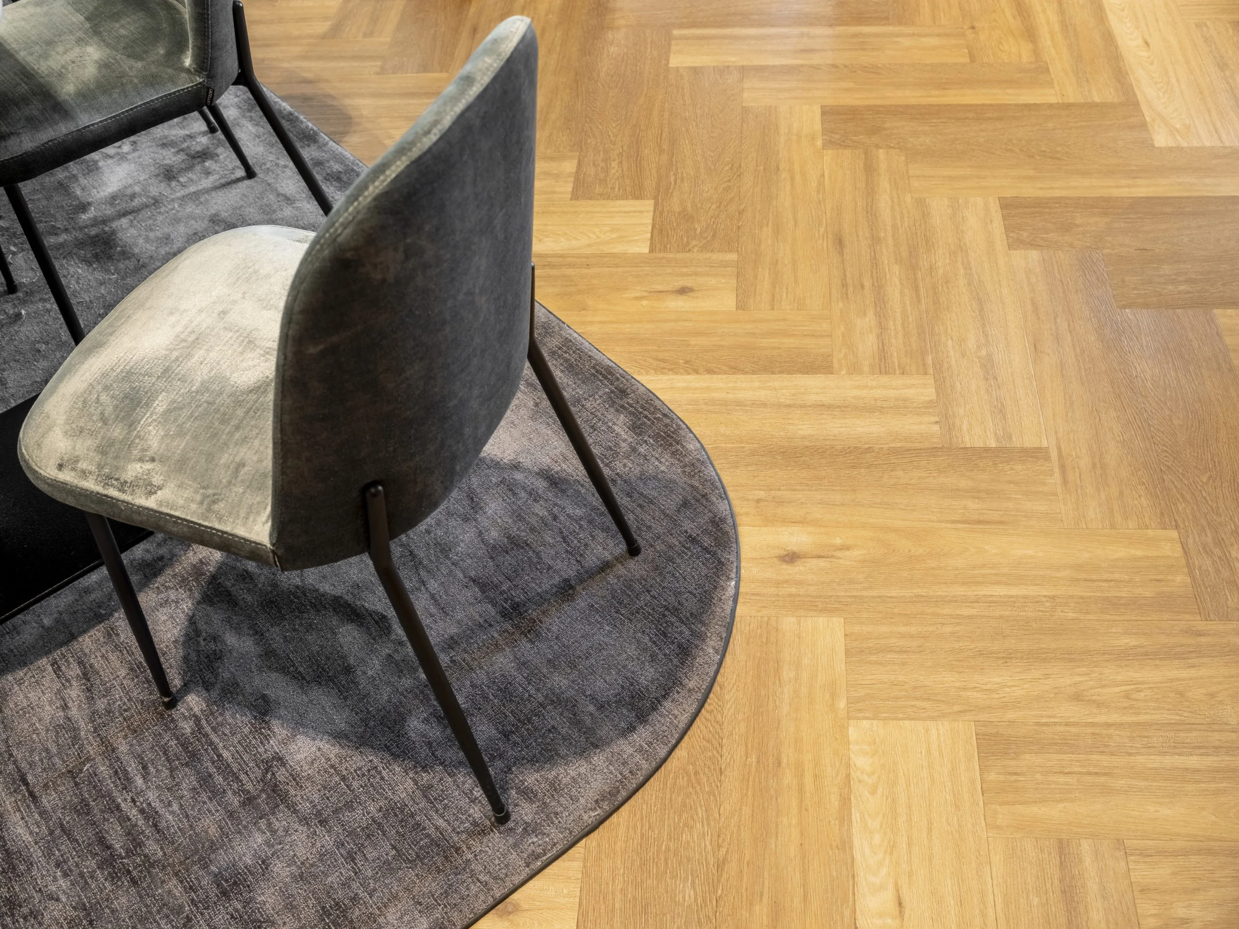 Axminster and Print Hospitality Carpets - suitable to pubs, clubs, hotels, bars:  A room with a wooden parquet floor, featuring gray upholstered chairs and a dark gray patterned carpet.