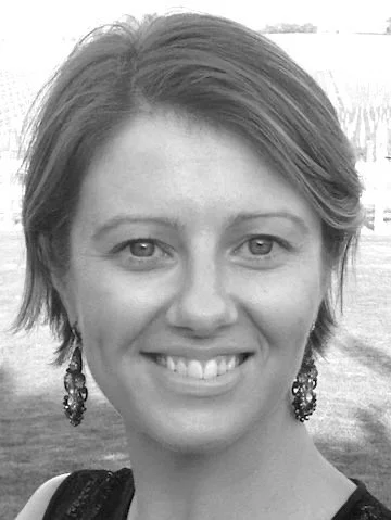 Black-and-white portrait of a smiling woman with short hair and earrings.