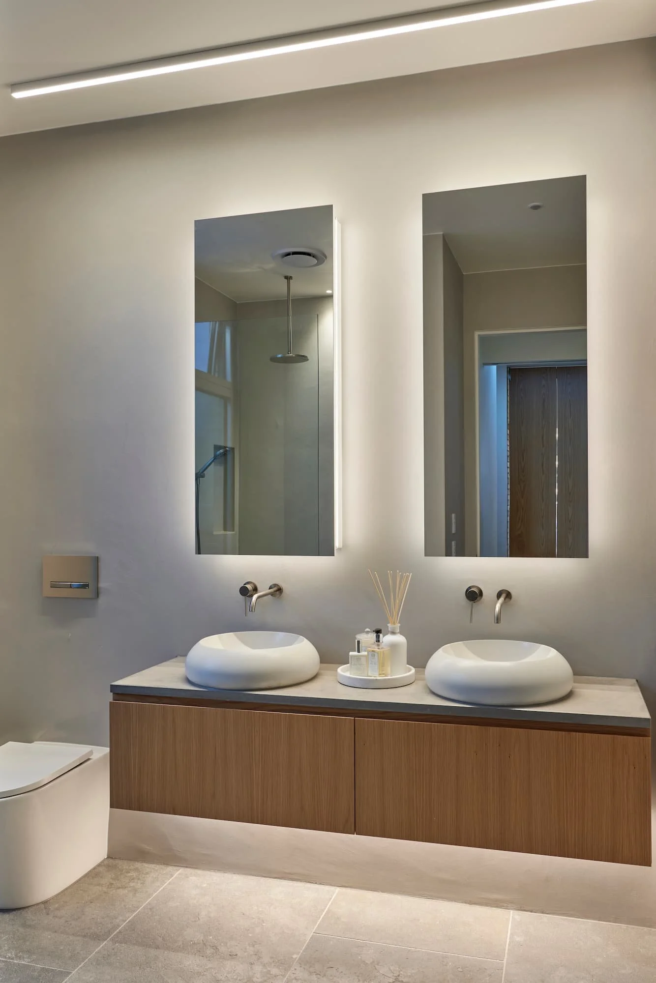 Bathroom with vanity and organic curved basins with backlit mirror cabinets
