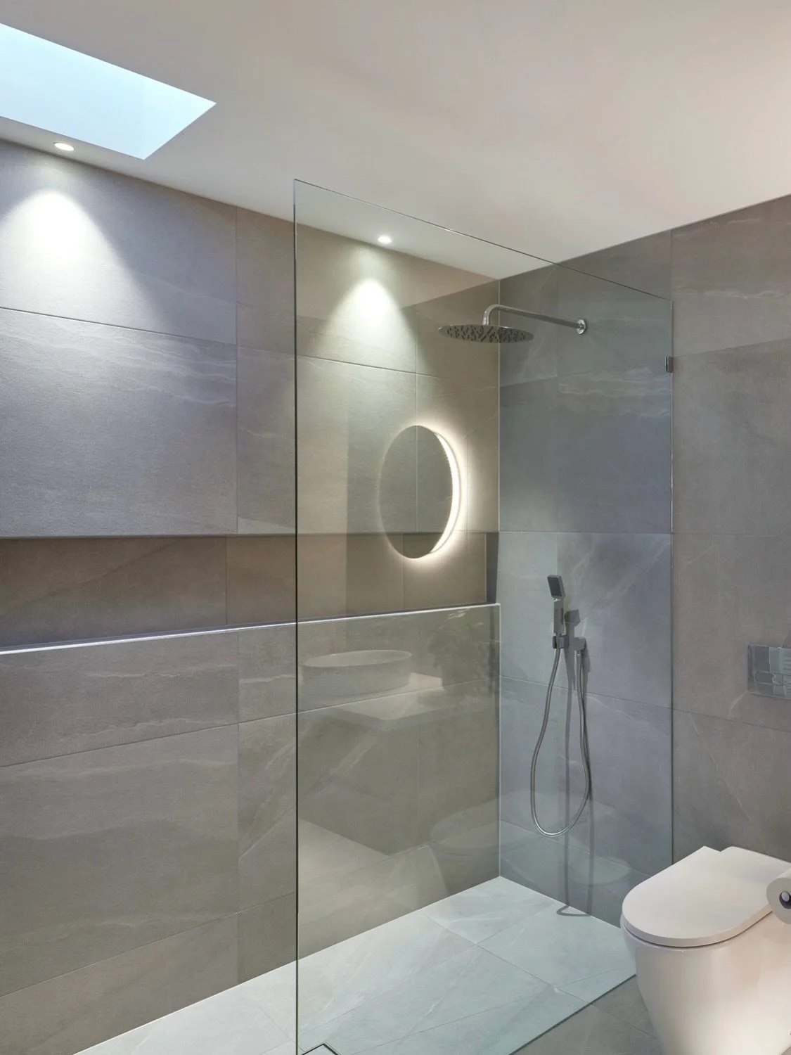 This bathroom beautifully shows the effect when there&rsquo;s no texture, just a rich depth of colour waiting to be brought to life by grazing the wall with light. 

Here, the large-format tiles in the shower create a smooth, moody environment, and w