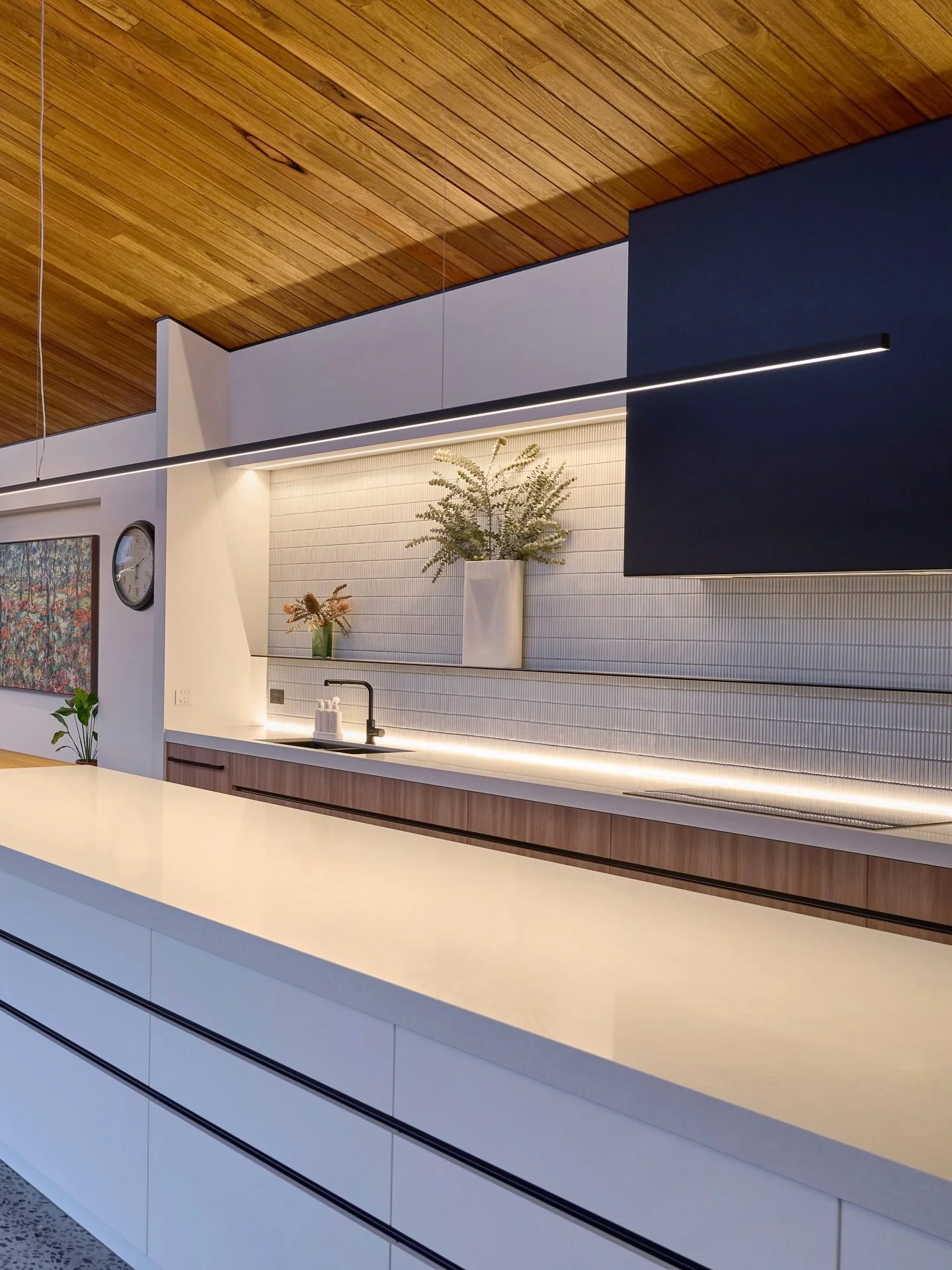 The large kitchen island is lit by a custom 4-metre linear pendant that delivers perfect functional light while remaining slimline and discreet in the space.

A metal shelf was used in the splashback, which meant we couldn&rsquo;t provide functional 