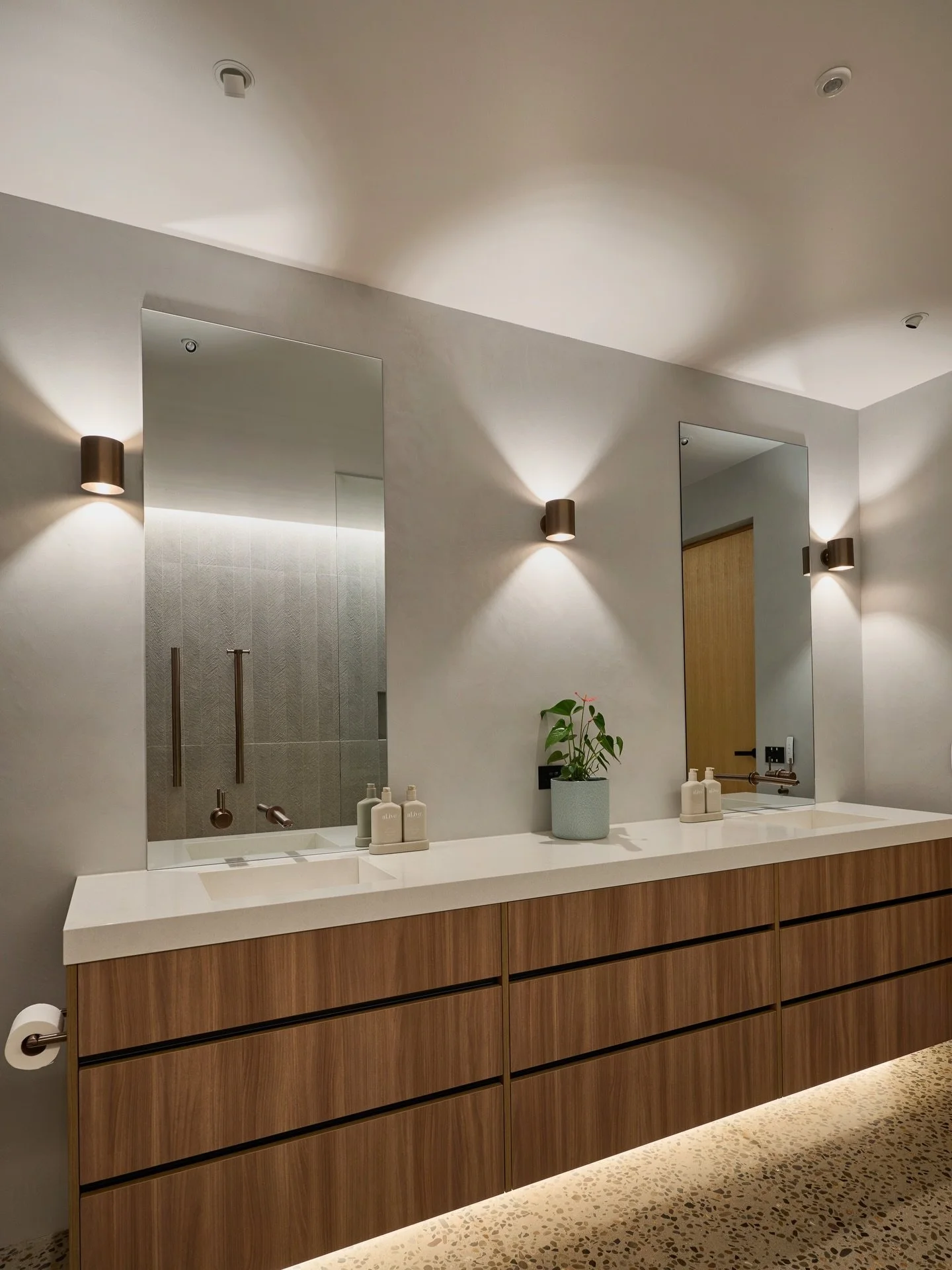 This family bathroom has a faux skylight that gently washes the shower with soft light, drawing out texture and creating a sense of calm. The decorative wall lights add a moment of drama, while ceiling spotlights provide the functional light needed f
