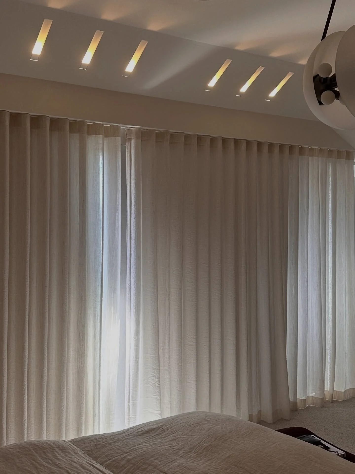 In the main bedroom of the Art House, the lighting becomes part of the architecture. We worked a series of trimless plaster recessed slot lights into the reveal in front of the doors, washing a soft, indirect glow across the ceiling surface, connecti