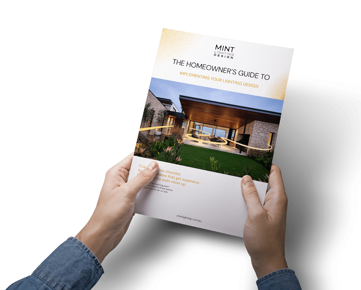 Hands holding a copy of the MINT Lighting Design homeowner's guide to implementing your lighting design