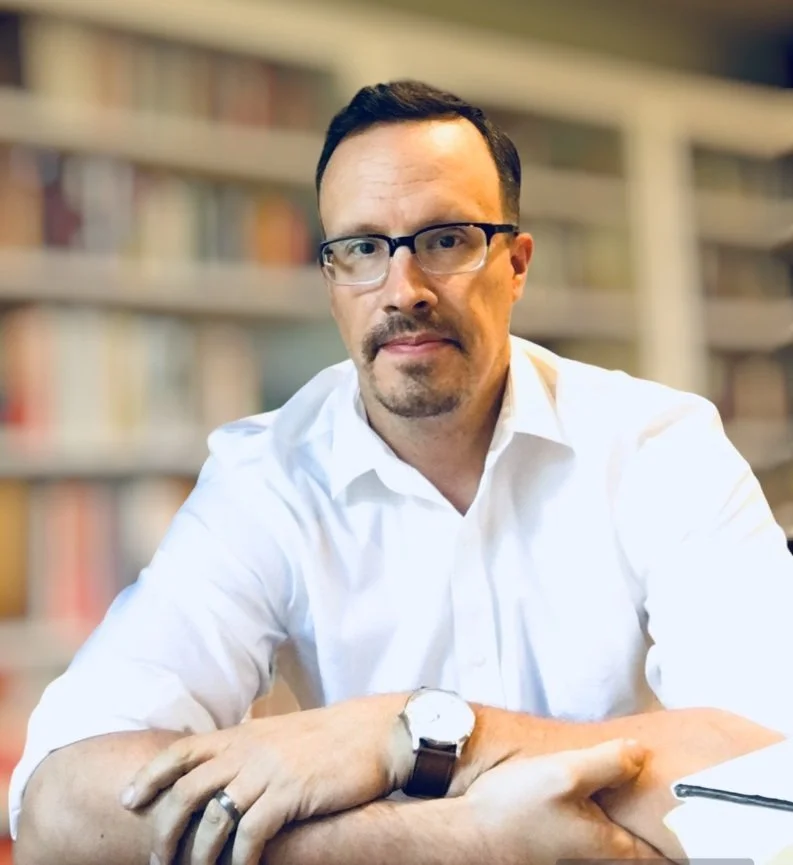 Man in white shirt with glasses in library setting
